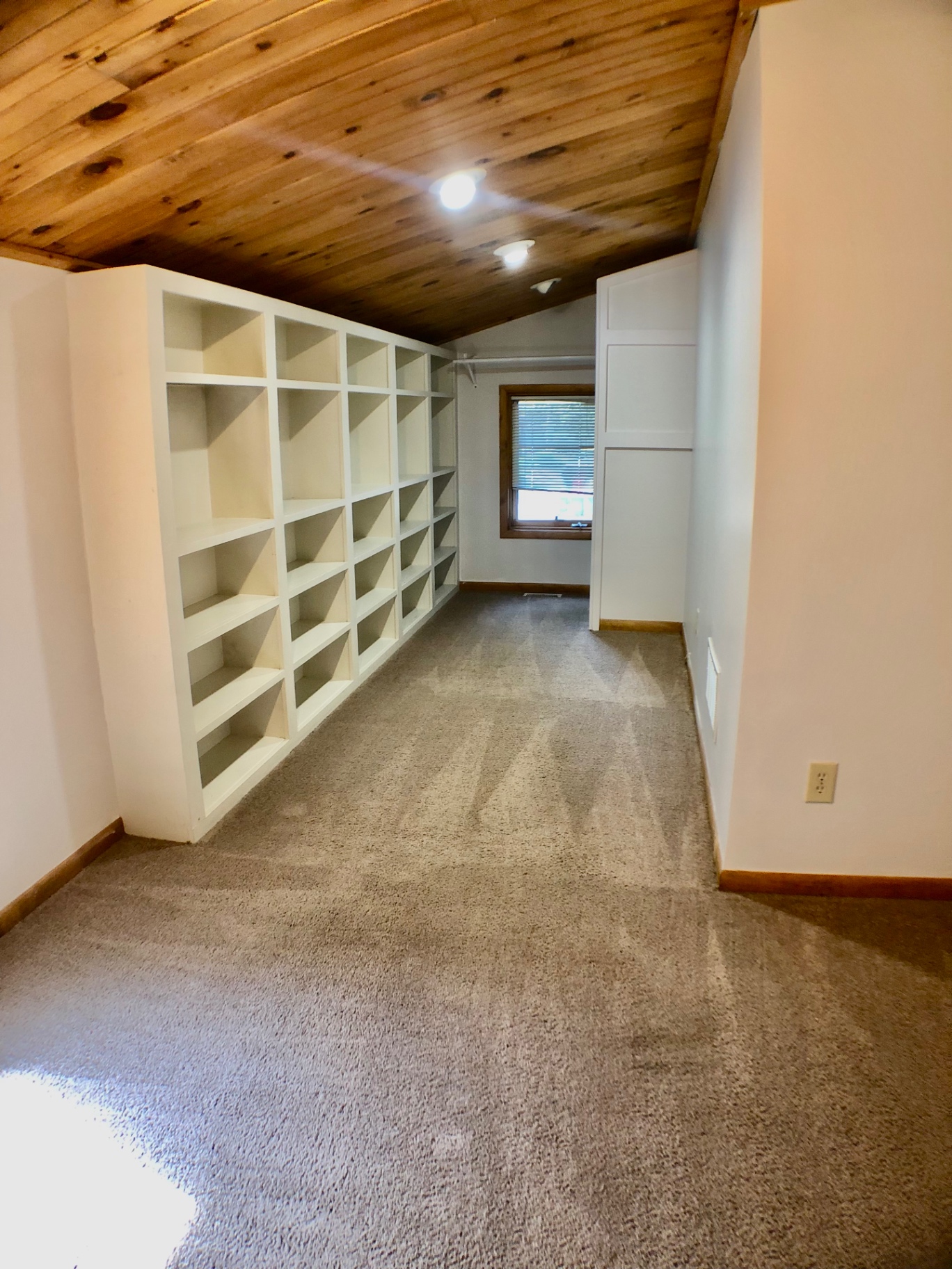 2040 Iuka Ave House loft area with wall of built-in white cube shelving and knotty pine ceiling