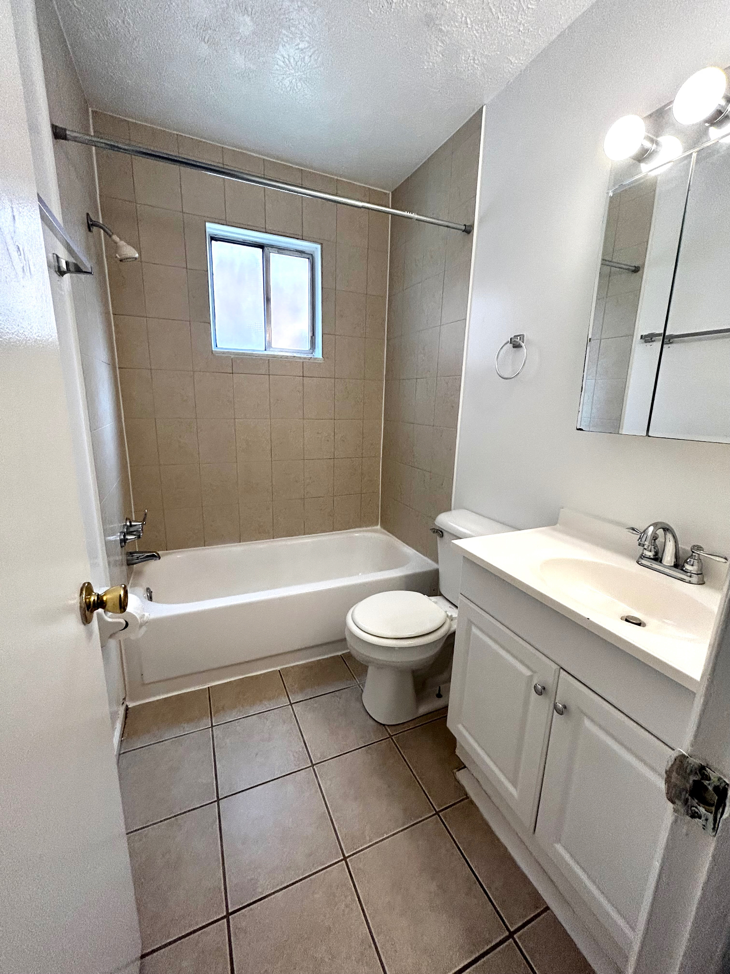 2150 N 4th St. Unit C full bathroom with tiled tub surround, window, and white vanity