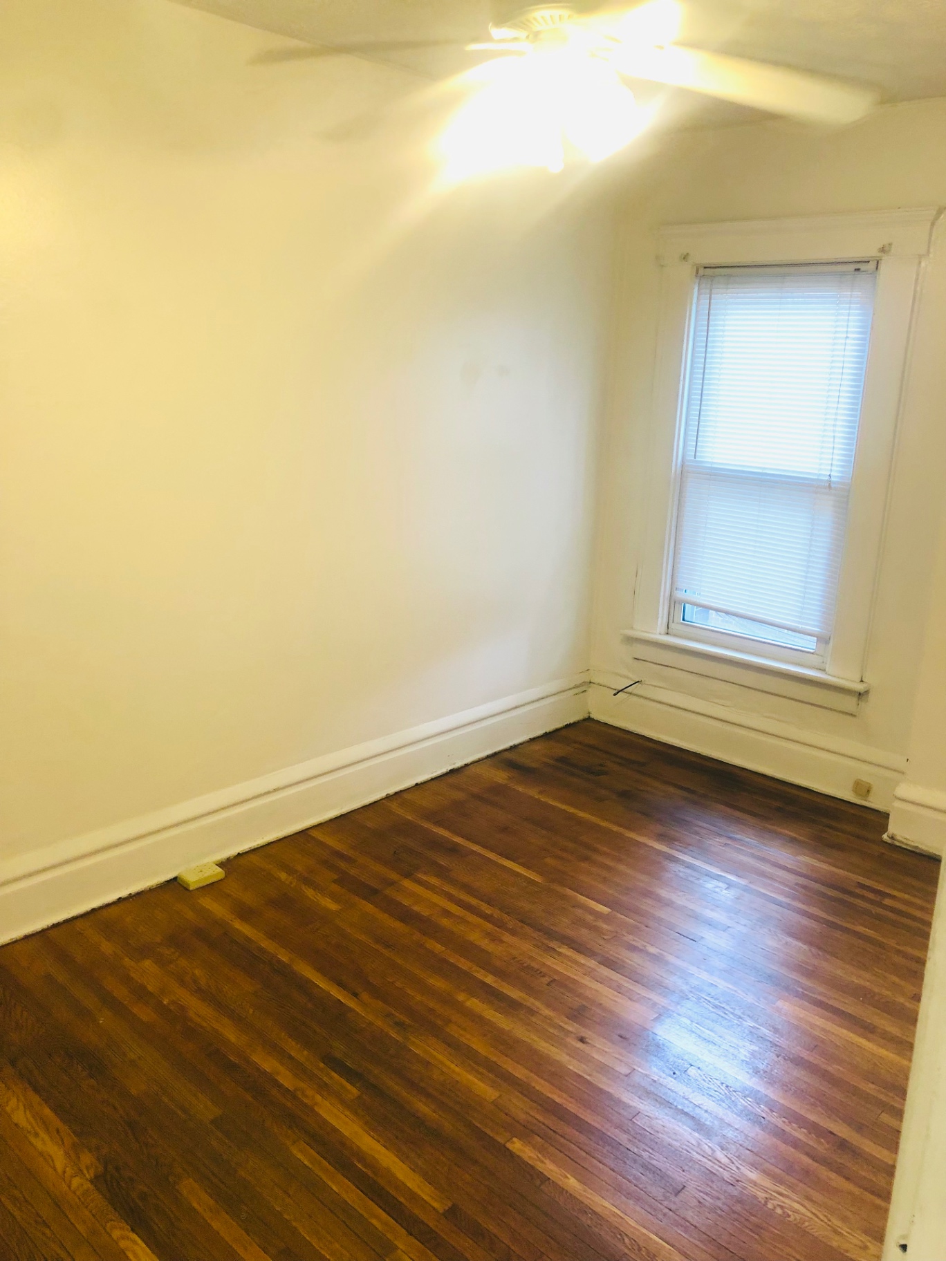 119 W 9th bedroom with refinished hardwood floors and bright window