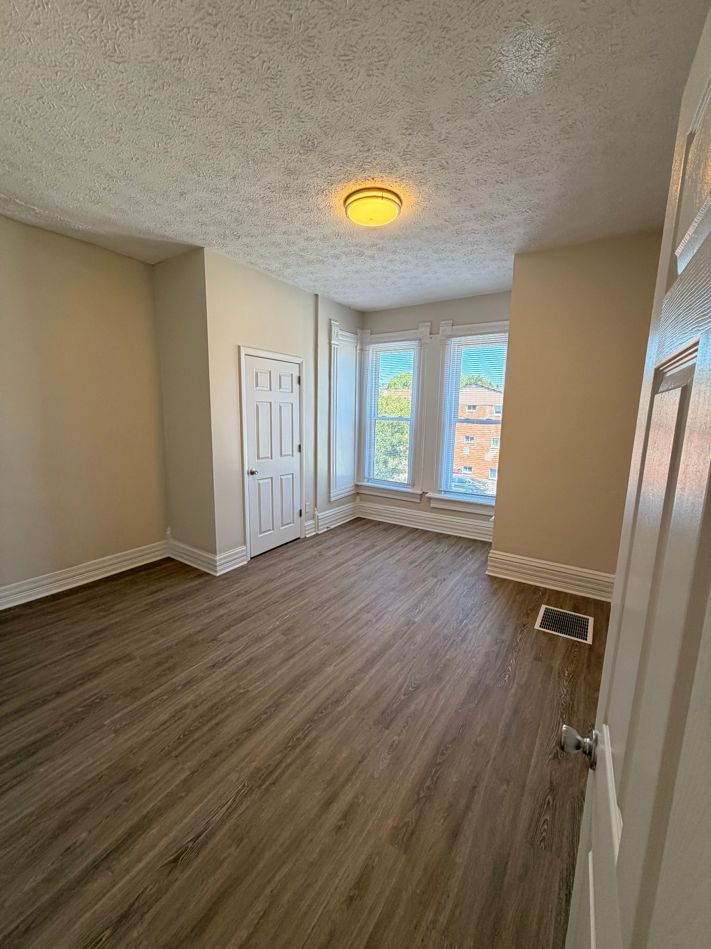 133½ bedroom with bay windows, plank flooring and high ceilings