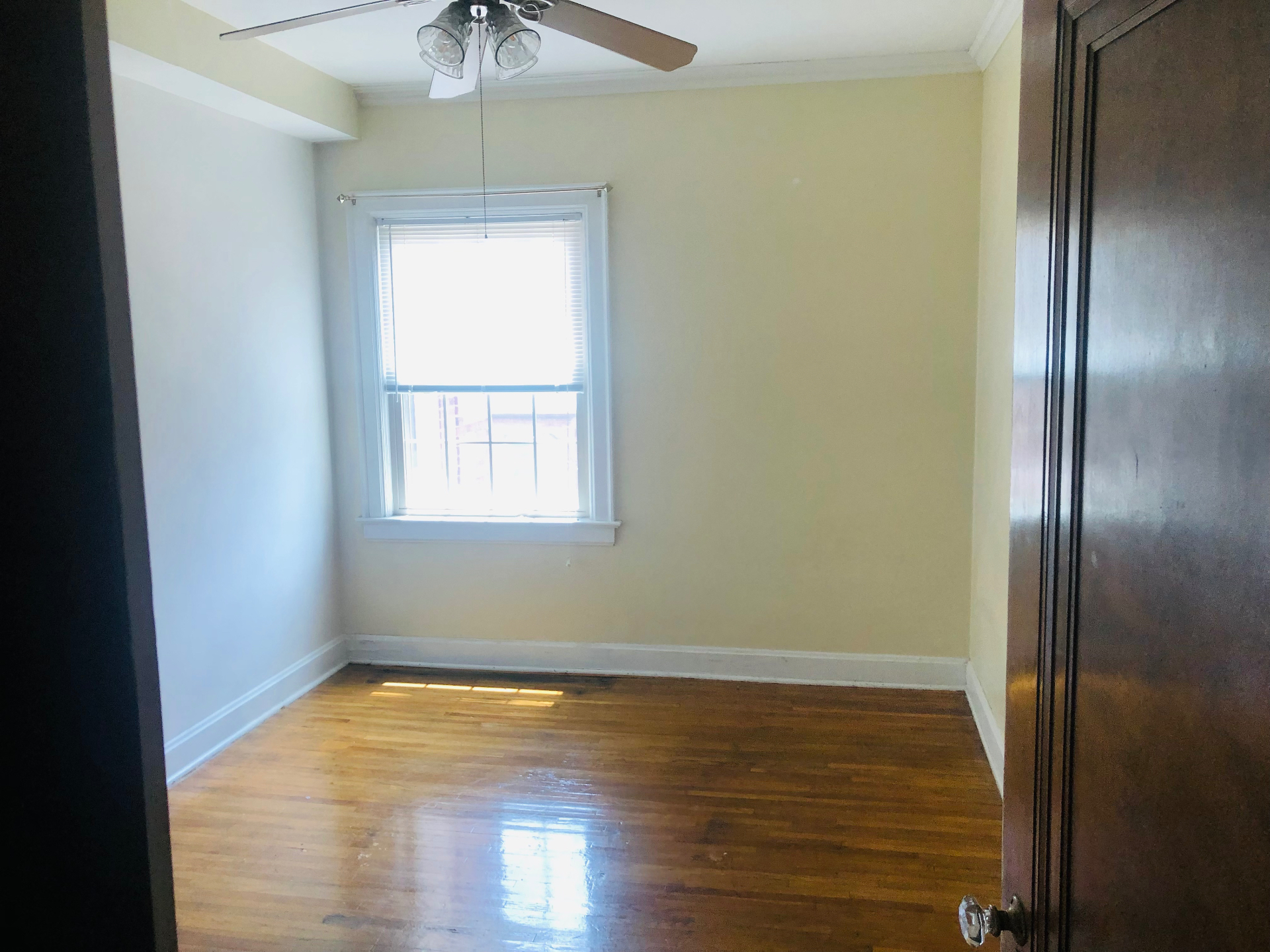 Unit K bedroom with hardwood floors, ceiling fan, and window