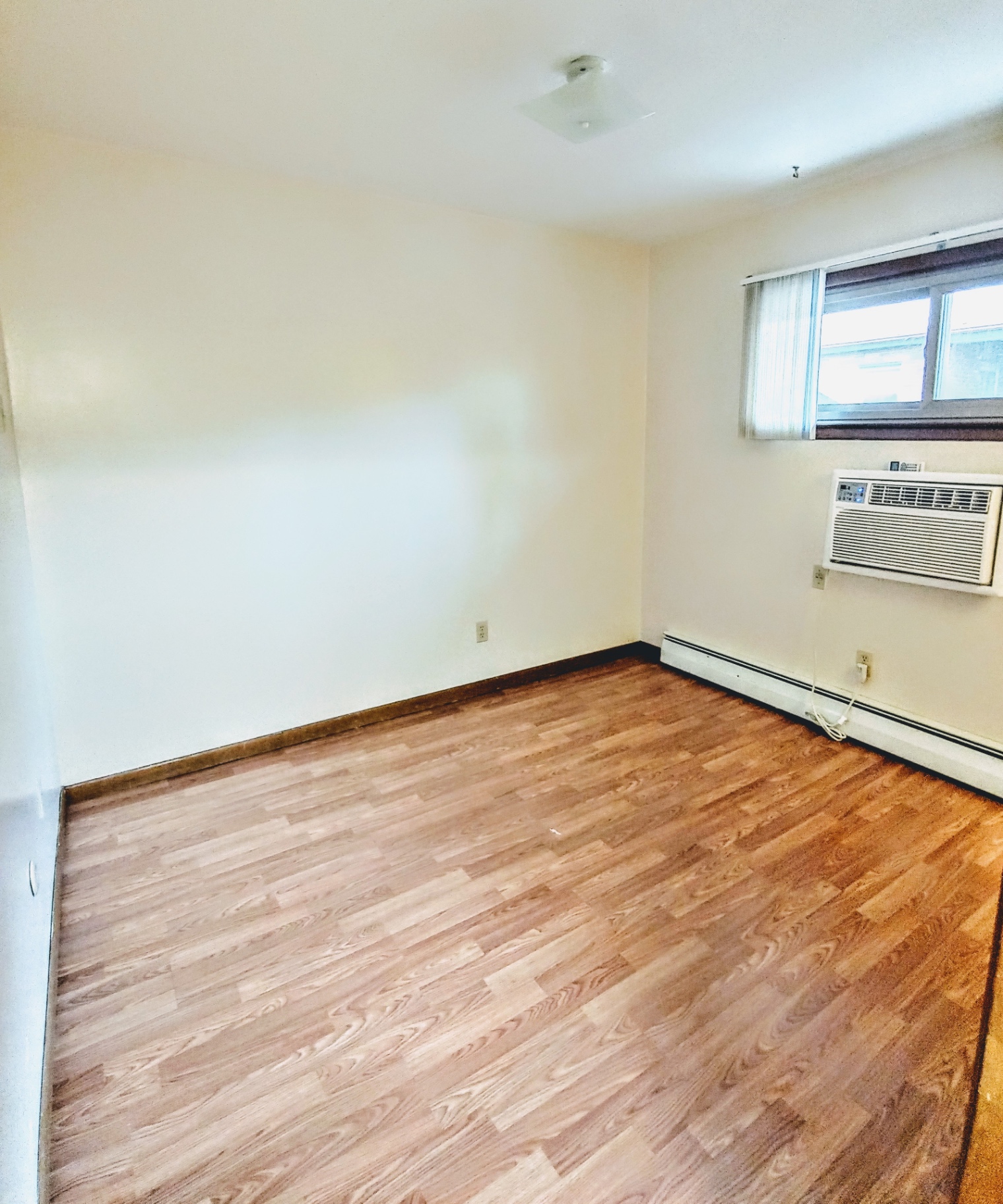 2040 Iuka Ave. 5B bedroom with wood laminate floors and window AC unit