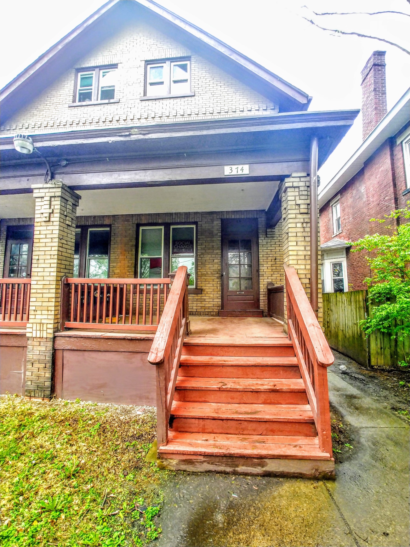 374 E 14th Ave. yellow-brick two-story house exterior with covered front porch and red steps