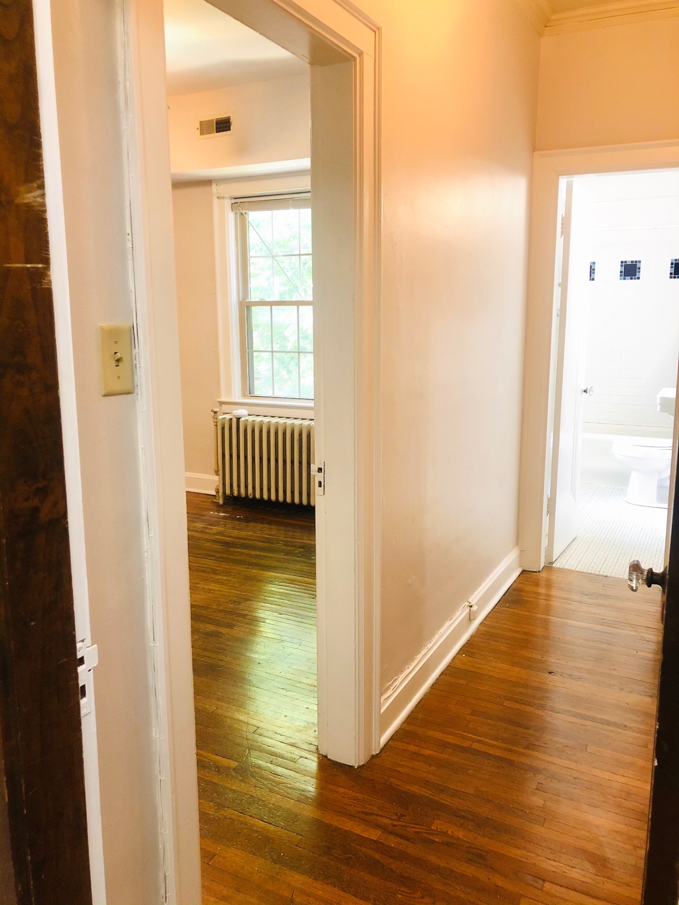 Unit L hallway with bedroom and bathroom entries and original hardwood floors