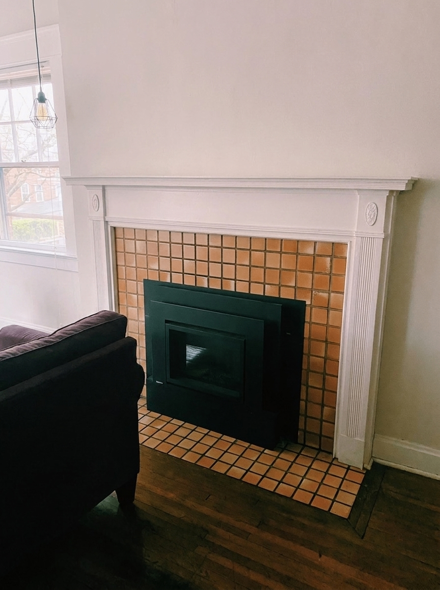 Unit H living room fireplace with white mantel and terracotta tile surround