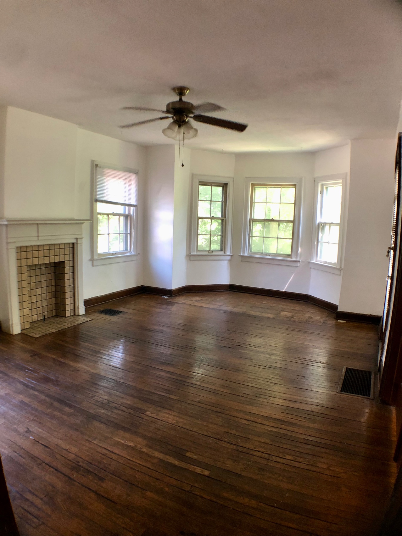 2044 Iuka Ave. A living room with decorative tile fireplace, ceiling fan, and bay window overlooking the ravine