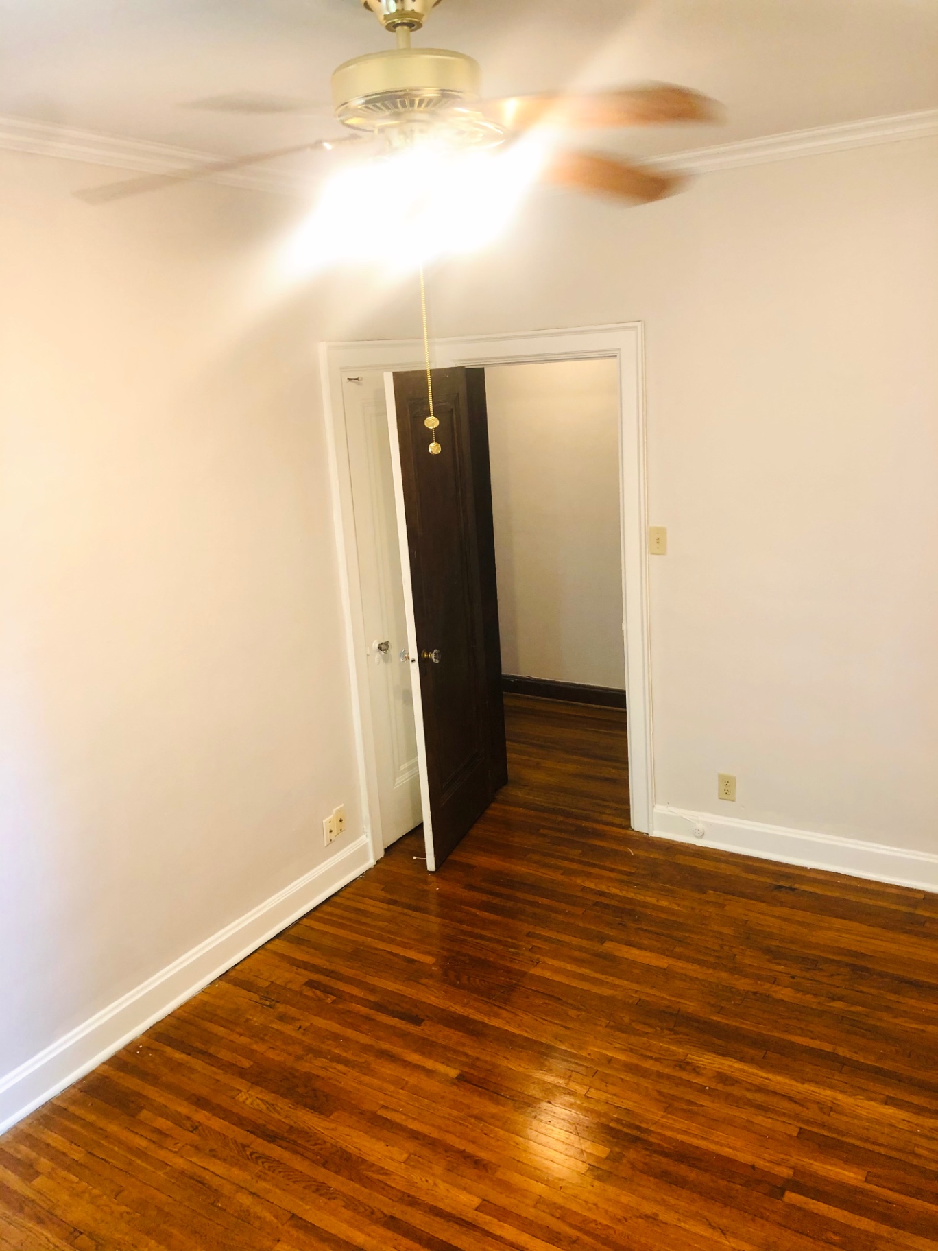 Unit L bedroom with dark hardwood floors and ceiling fan