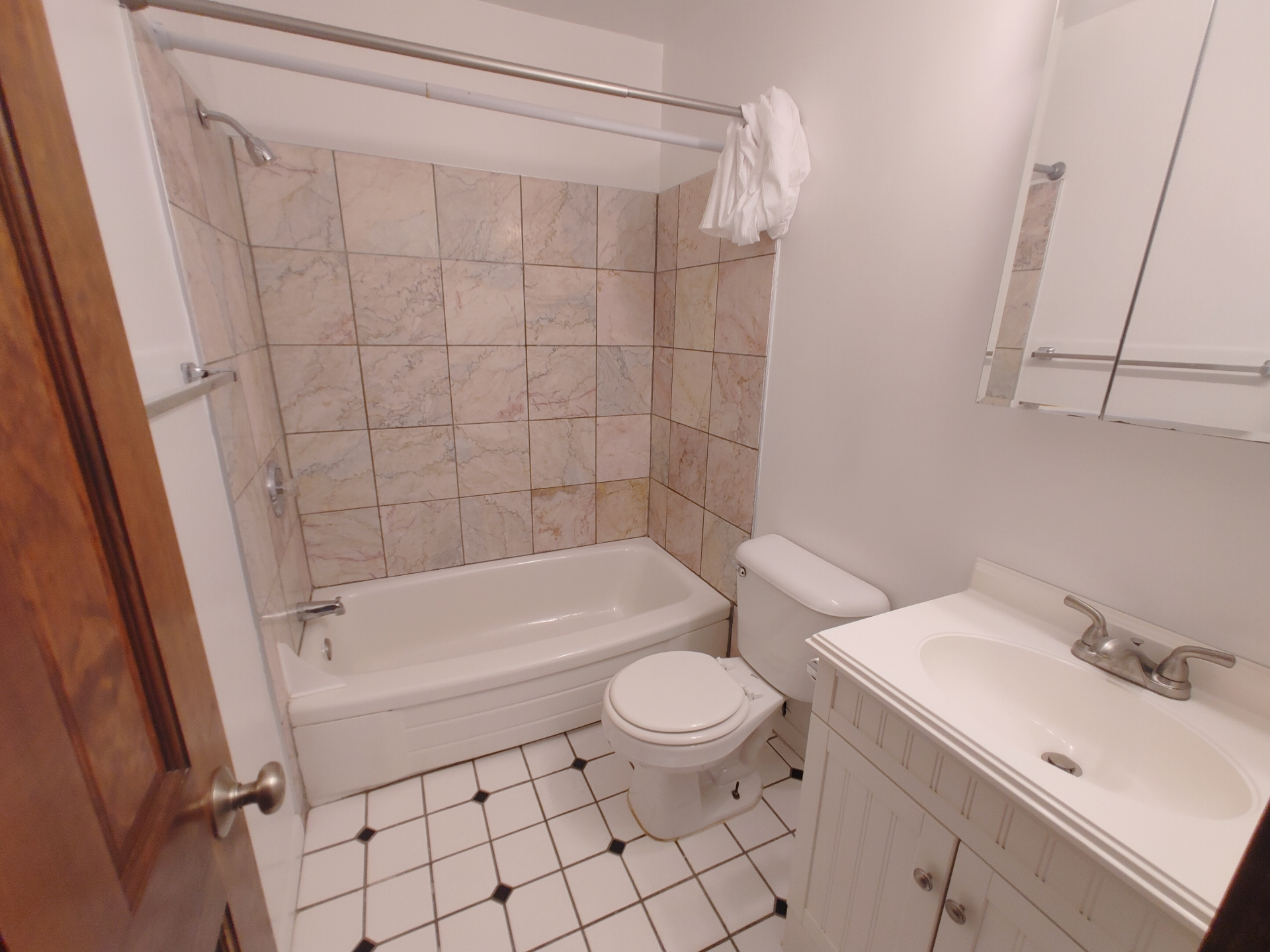 1827 N 4th St. Unit 6 bathroom with tiled tub surround, white vanity, and black-and-white tile floor