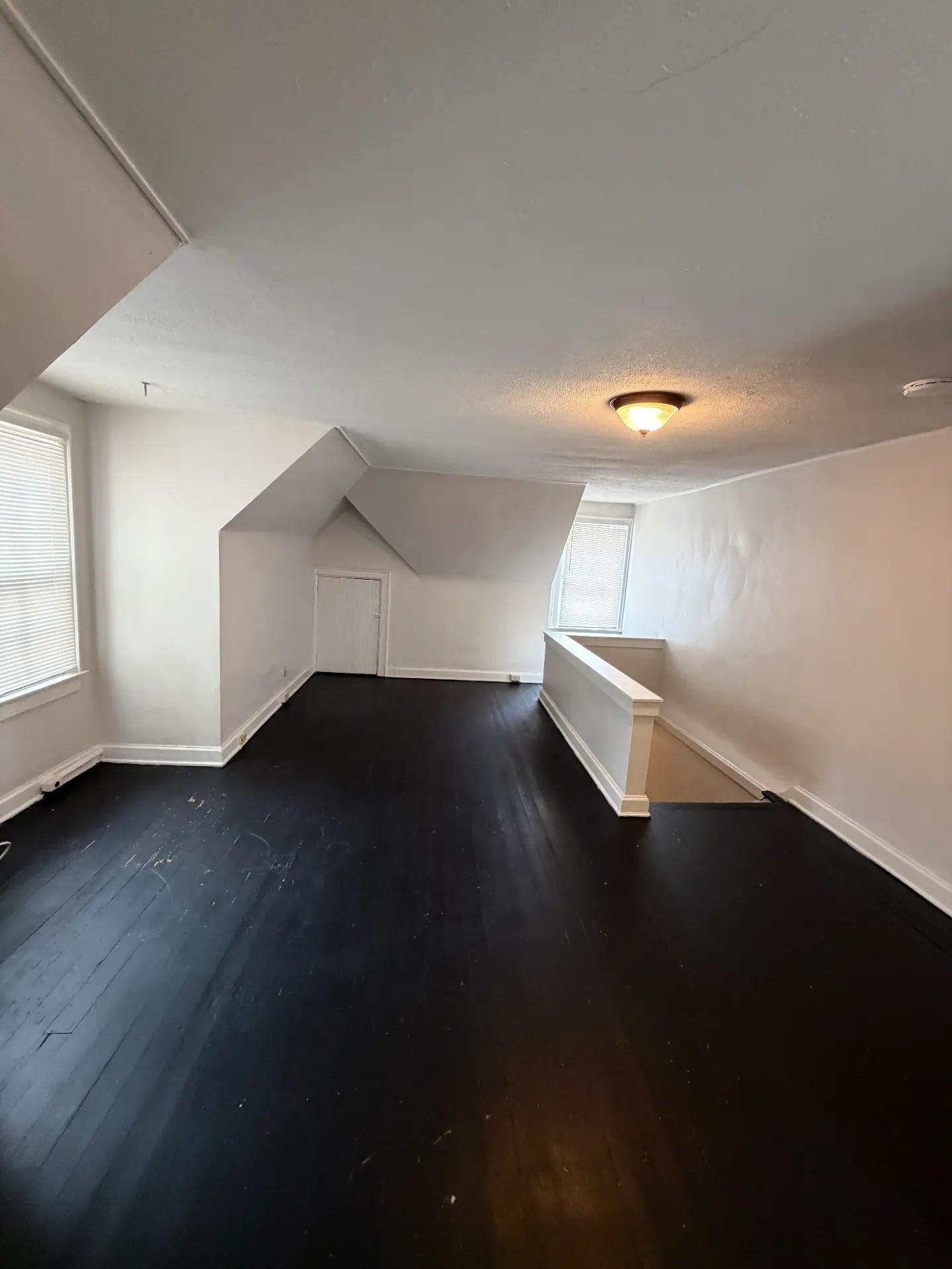 2048 Iuka Ave. D upper-level loft with painted black hardwood floors, dormer alcove, and stair railing