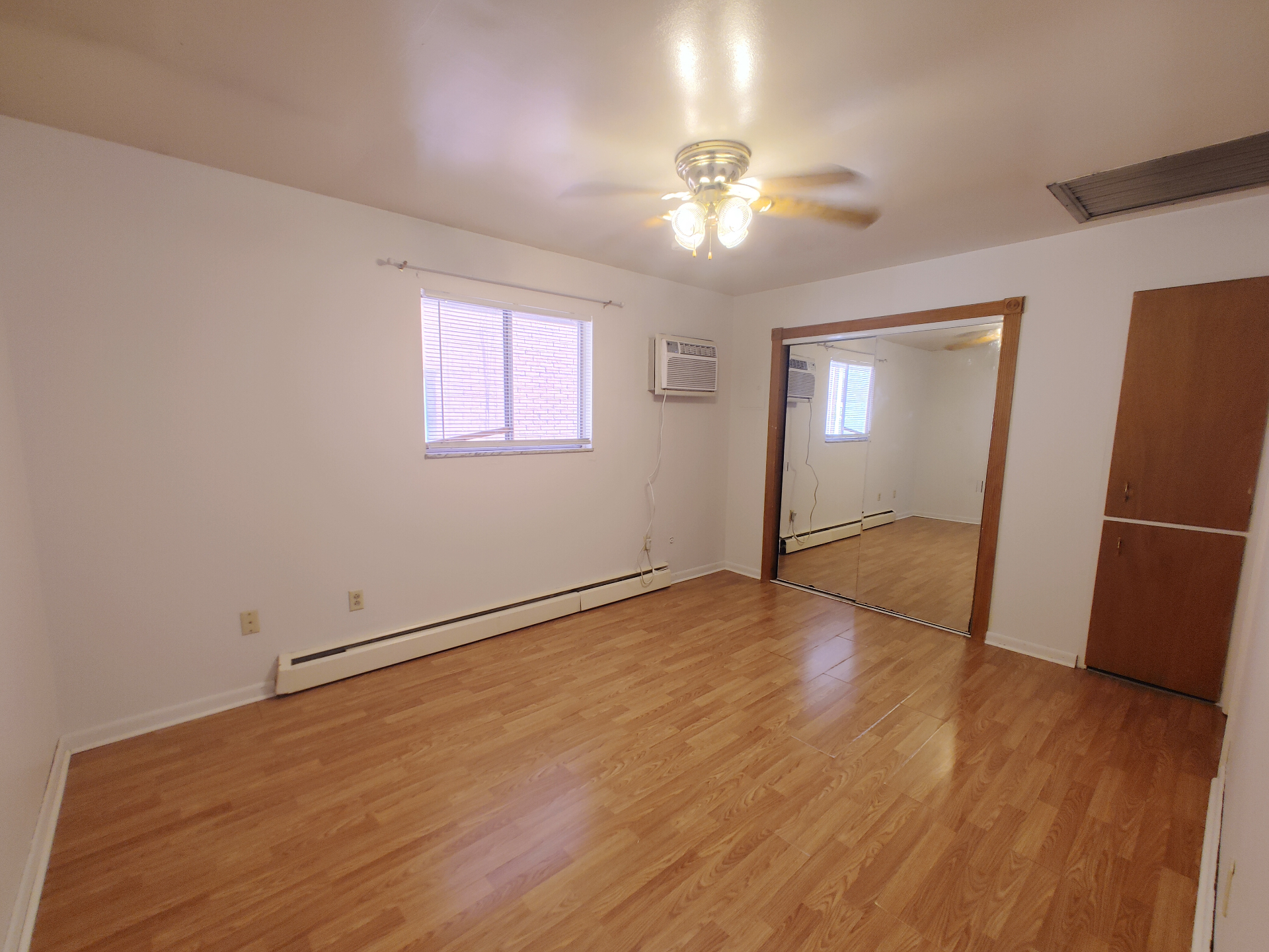 1827 N 4th St. Unit 5 bedroom with wood-look flooring, ceiling fan, mirrored closet, and window AC