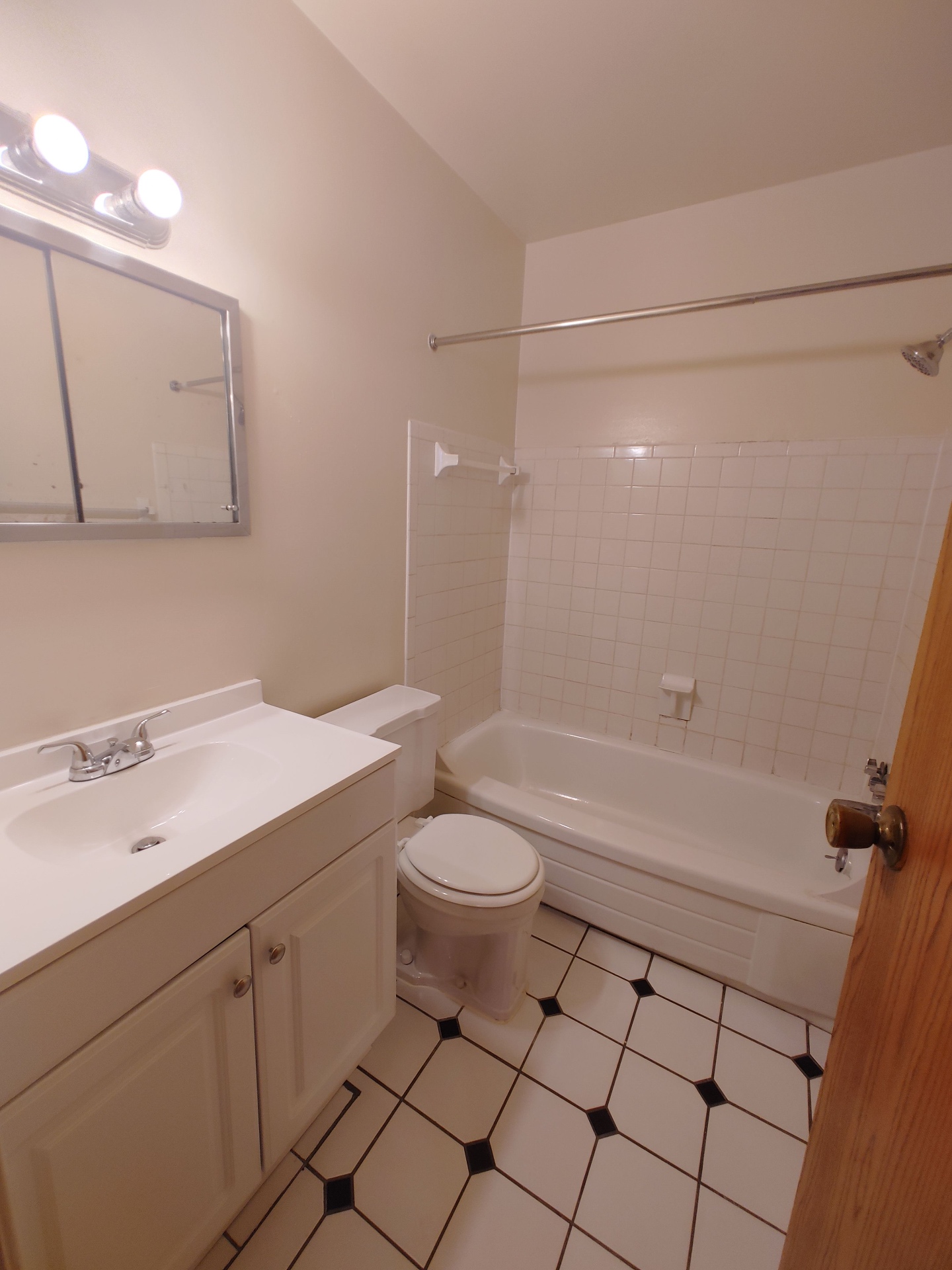 1827 N 4th St. Unit 5 bathroom with white vanity, tiled tub/shower, and checkered tile floor