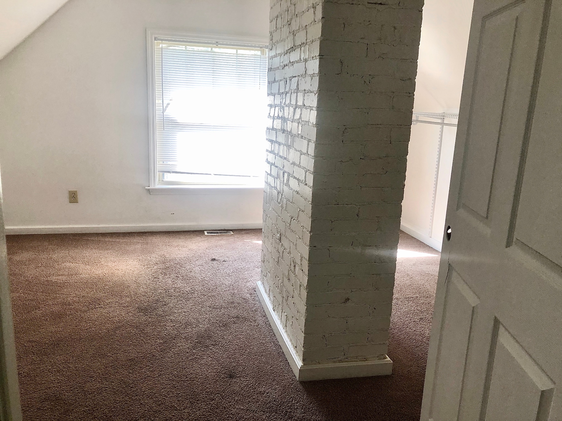 2034 Iuka Ave A upstairs bedroom with exposed painted brick chimney and closet
