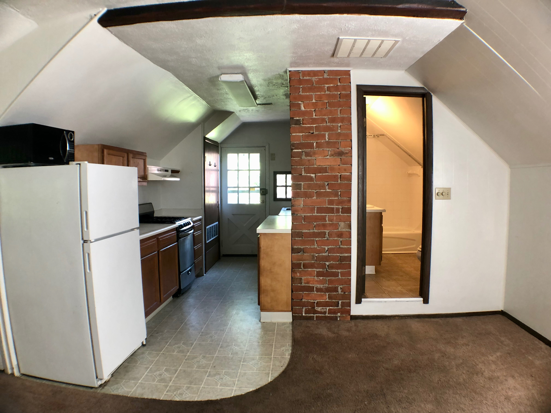 Kitchen looking toward bathroom entry and exposed brick divider