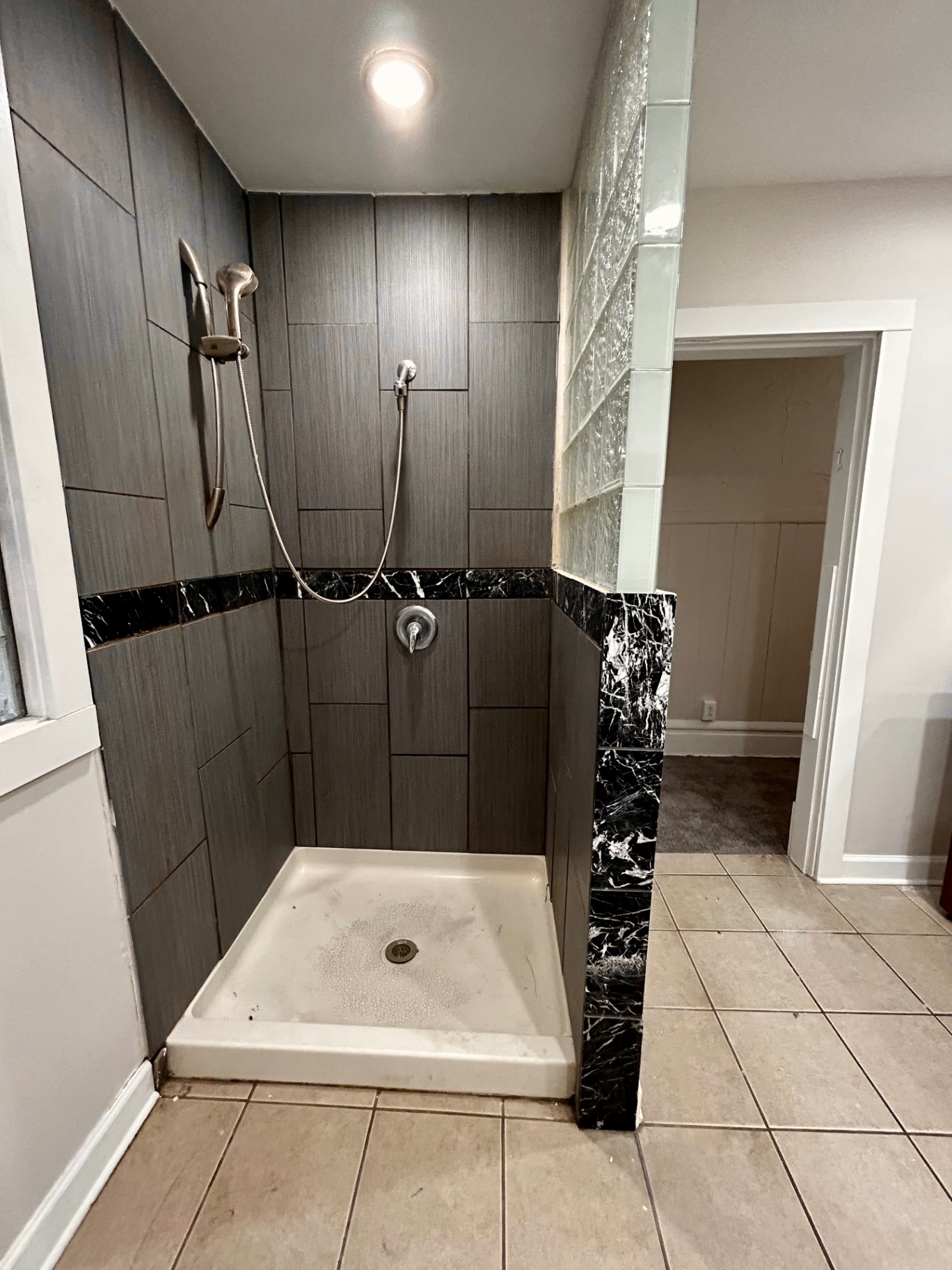 68 E Patterson Ave. walk-in tile shower with dark tile surround, marble accents, and glass block wall