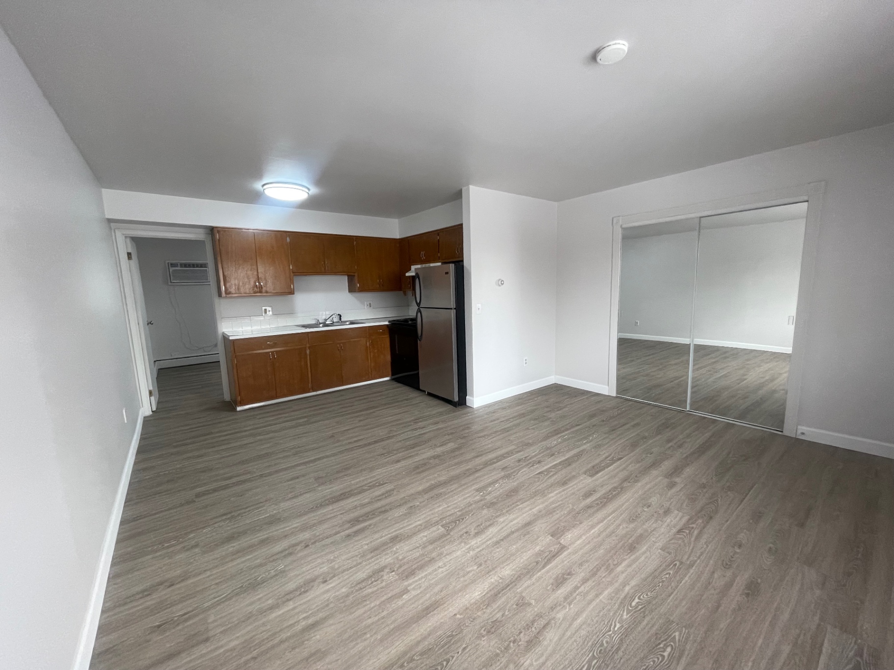 1827 N 4th St. Unit 8 open living room with wood-look flooring, mirrored closet doors, and view into kitchen