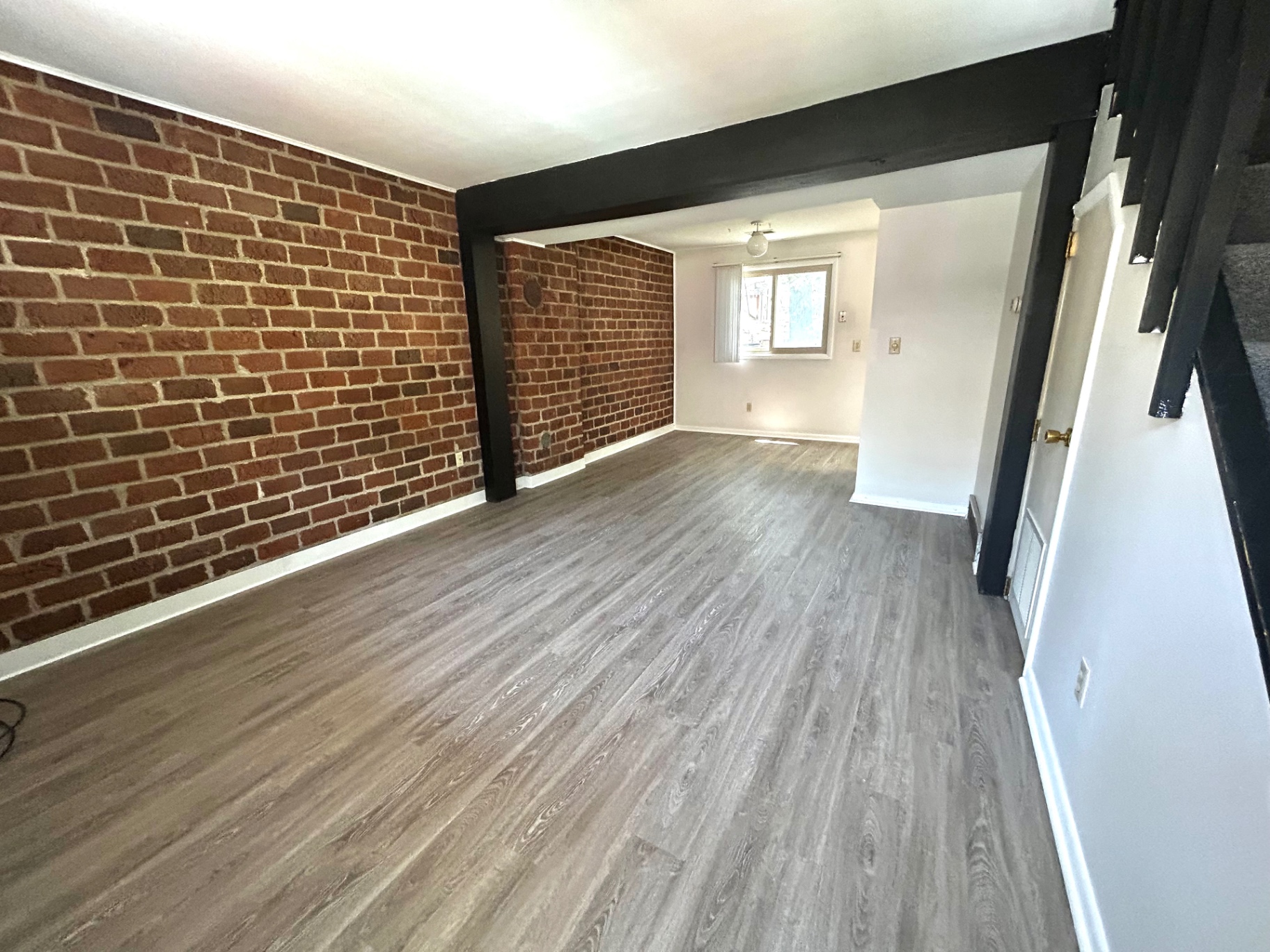 2011 Summit St. Unit E wide living/dining area with double brick accent walls and dark plank floors