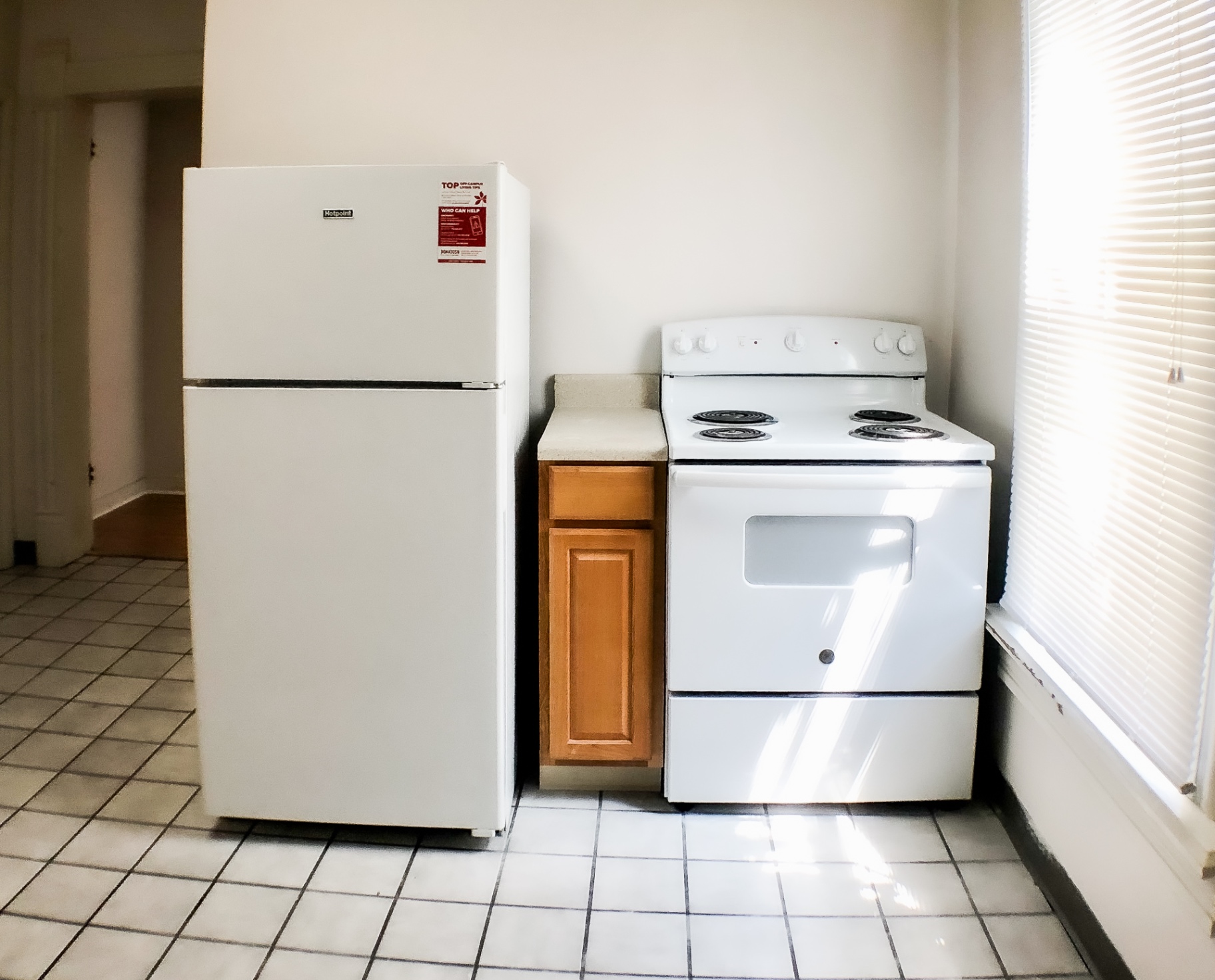 Unit A kitchen appliances — fridge and electric range next to bright window