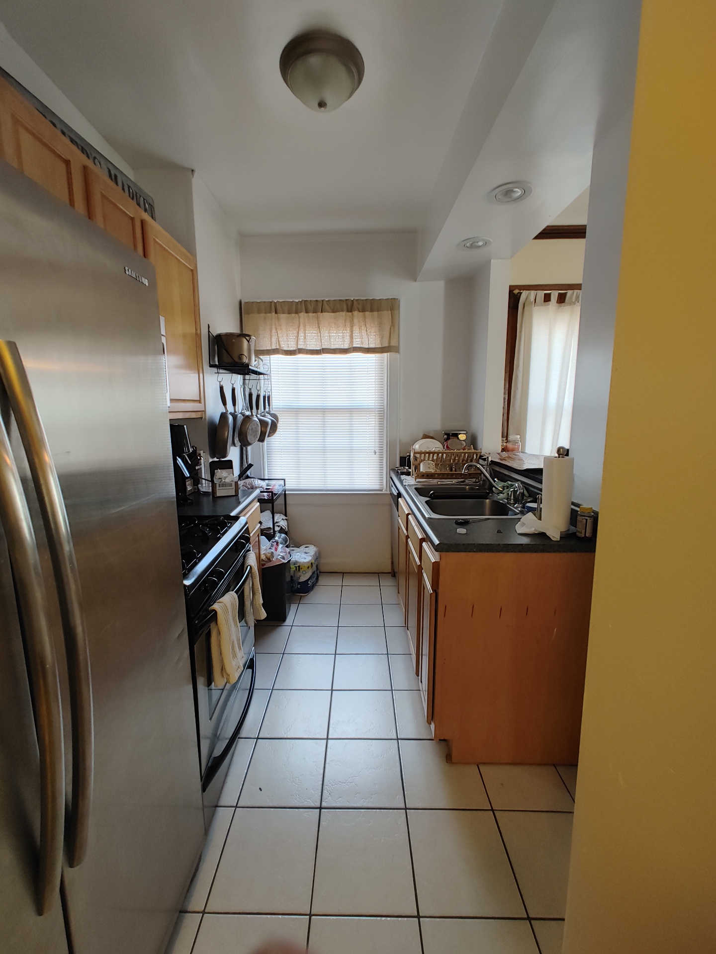 Unit G galley kitchen with stainless refrigerator, gas range, and double sink