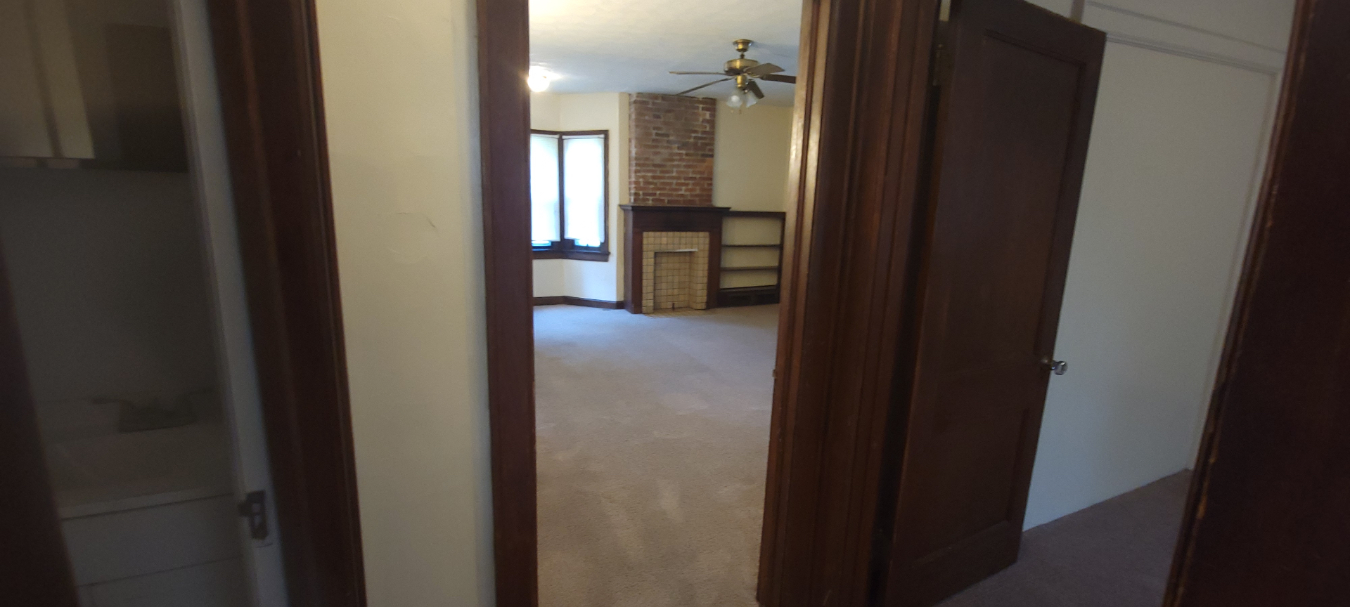 2054 Iuka Ave. C view from hallway into living room showing brick fireplace and built-in shelving