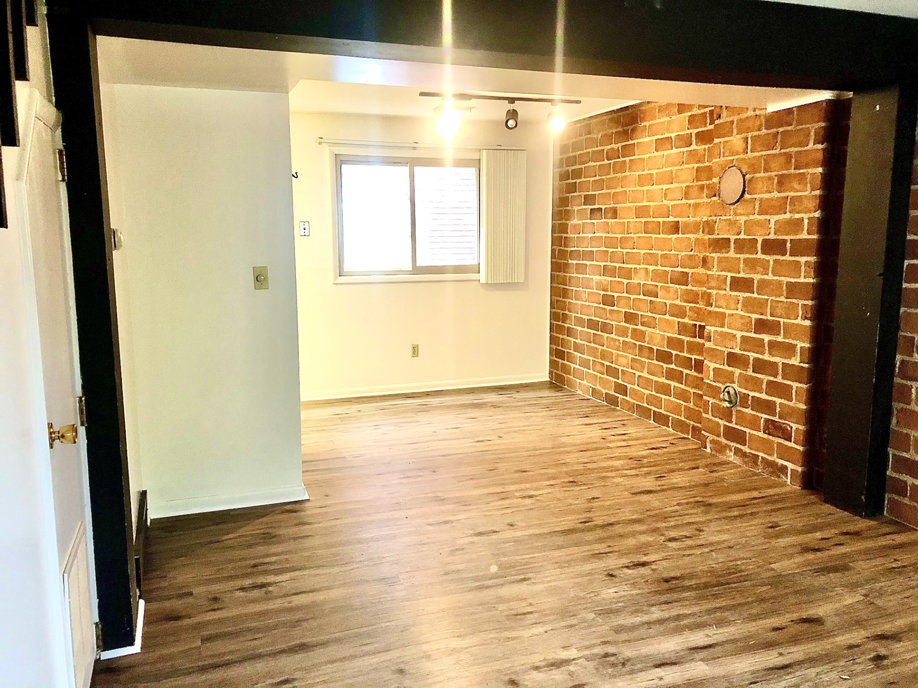 2011 Summit St. Unit A living space with exposed red brick accent wall, plank floors, and track lighting