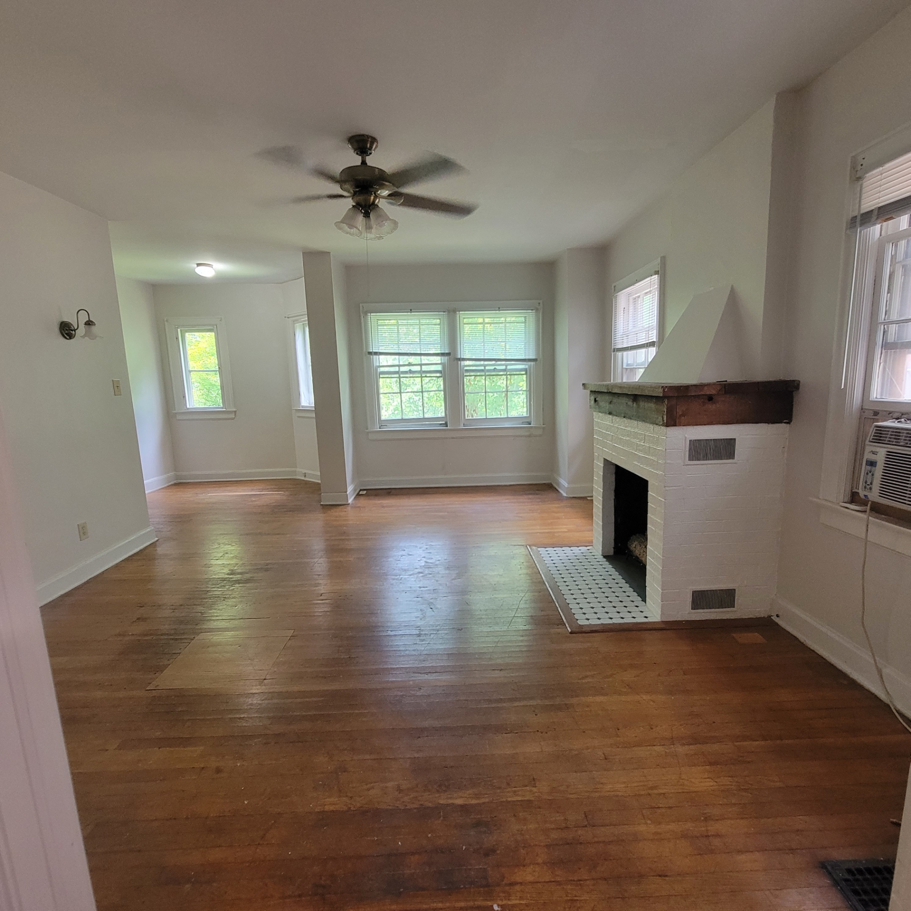 2048 Iuka Ave. C spacious living/dining area with tall windows, hardwood floors, and decorative fireplace