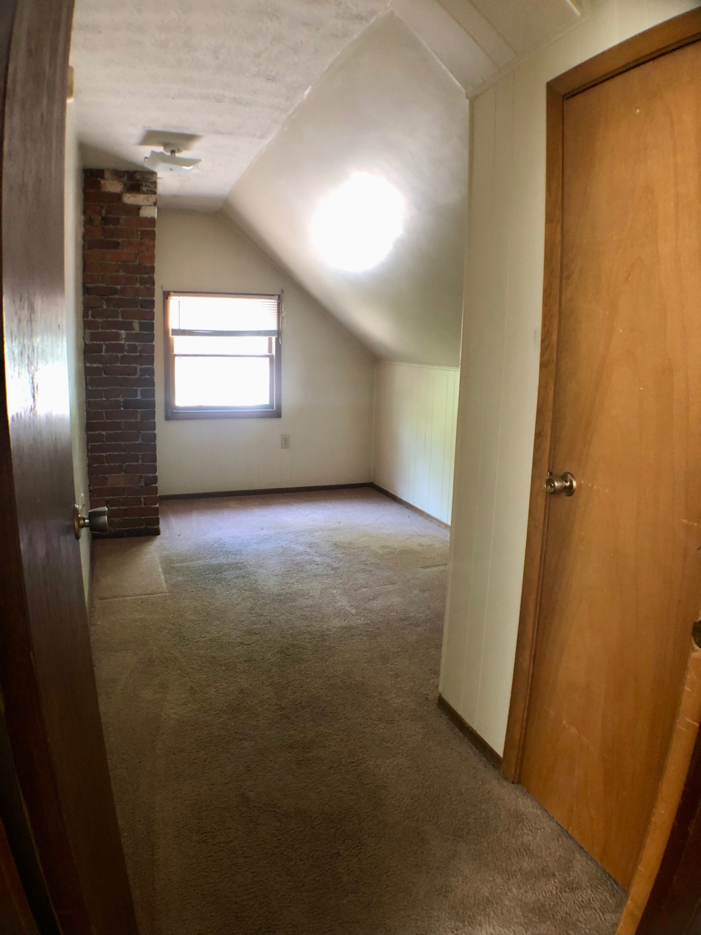Bedroom with exposed brick chimney and bright window with blinds
