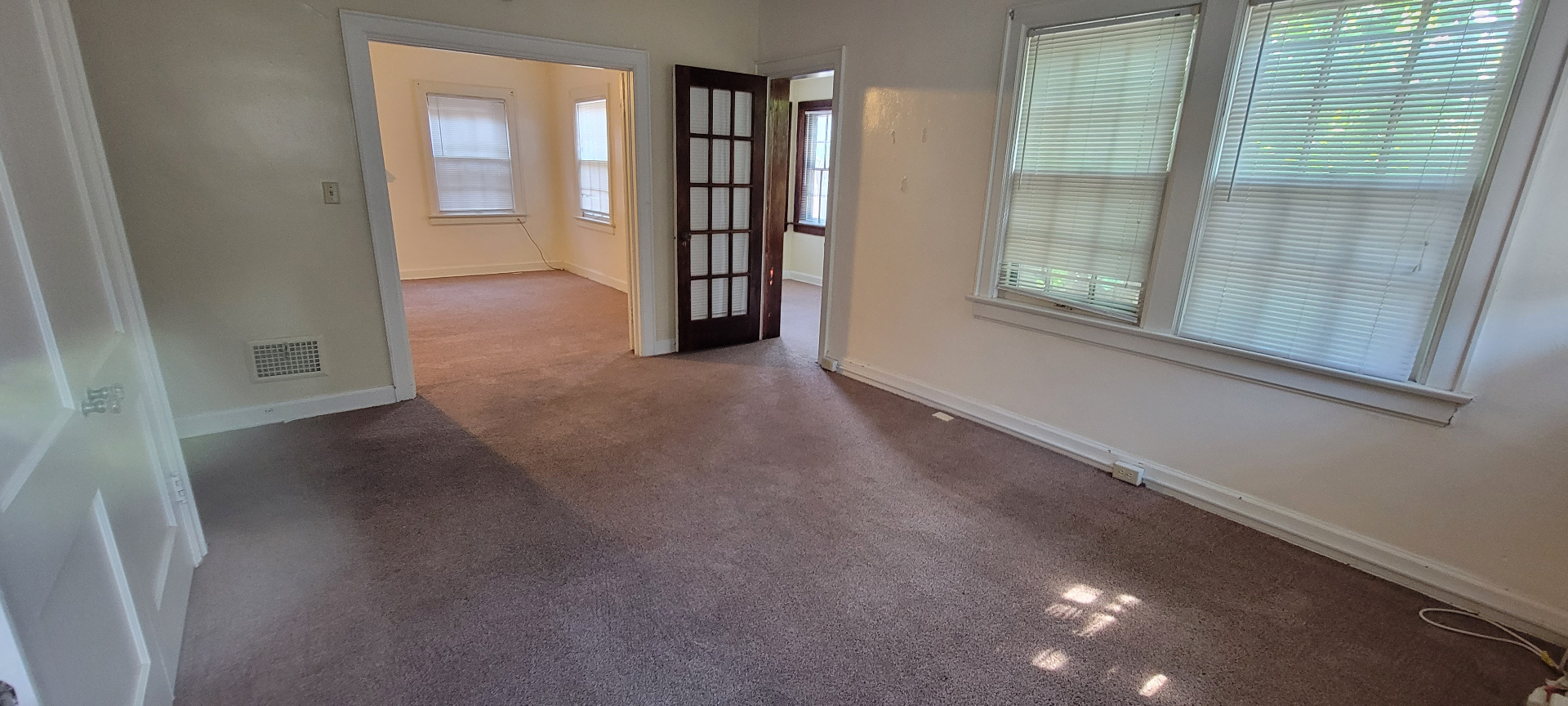 2044 Iuka Ave. D living room with original dark-stained French door opening to an adjoining sunlit room