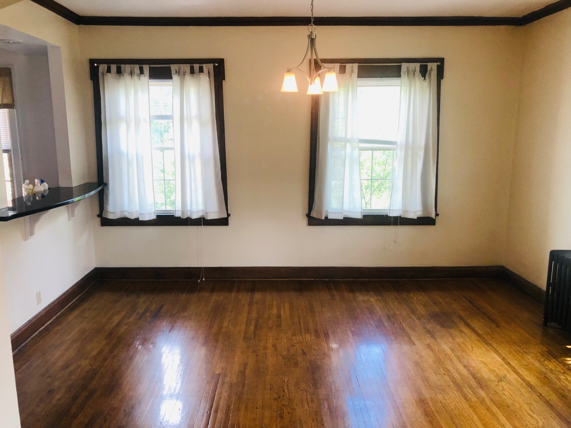 Unit K dining room with two large windows, chandelier, and dark wood trim