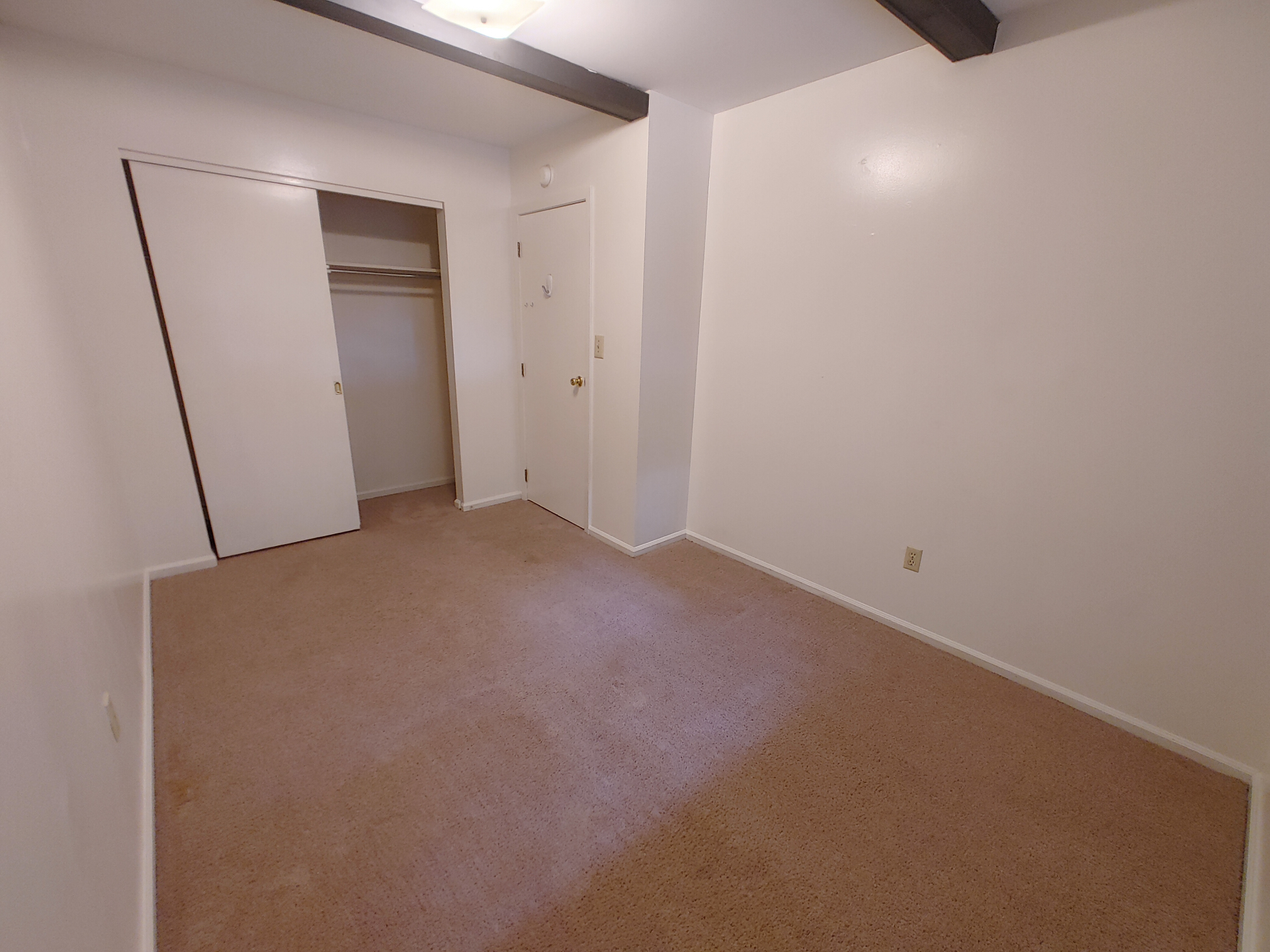 2016 Iuka Ave. bedroom with sliding closet doors, fresh carpet, and exposed ceiling beam