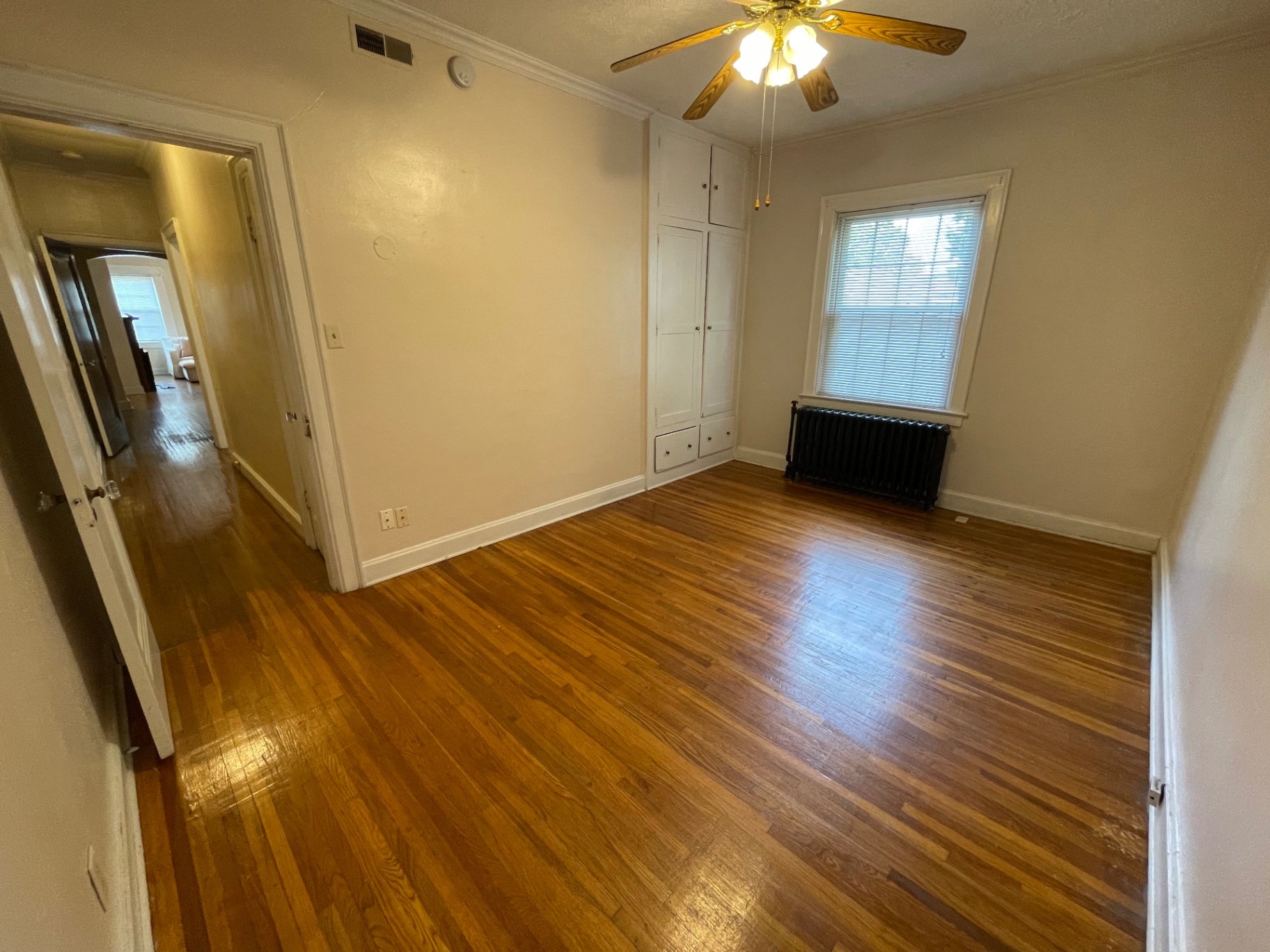 Unit E bedroom with built-in cabinetry and radiator