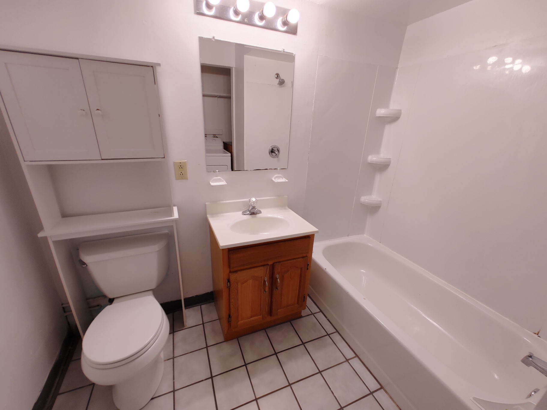 Rear unit bathroom with tub/shower surround, wood vanity and upper storage