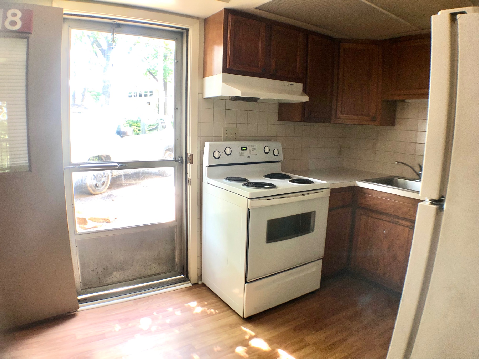 2018 Iuka Ave. kitchen with white appliances, wood cabinets, tile backsplash, and door to outside