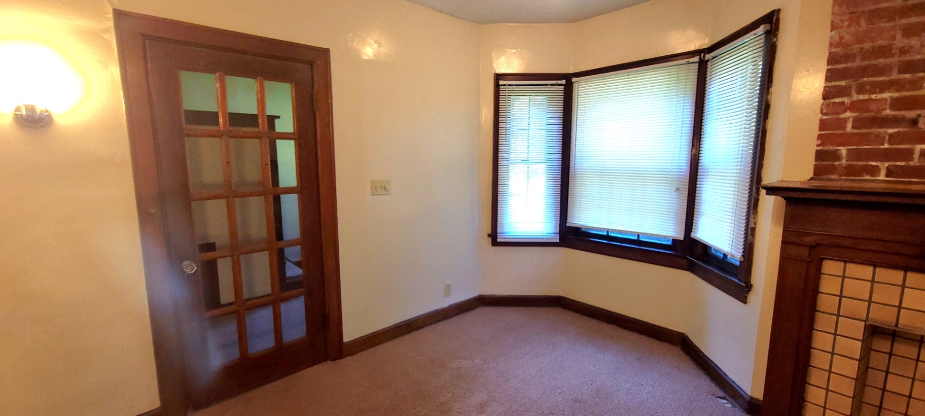 2054 Iuka Ave. C original French door with divided glass panes next to bay window and fireplace