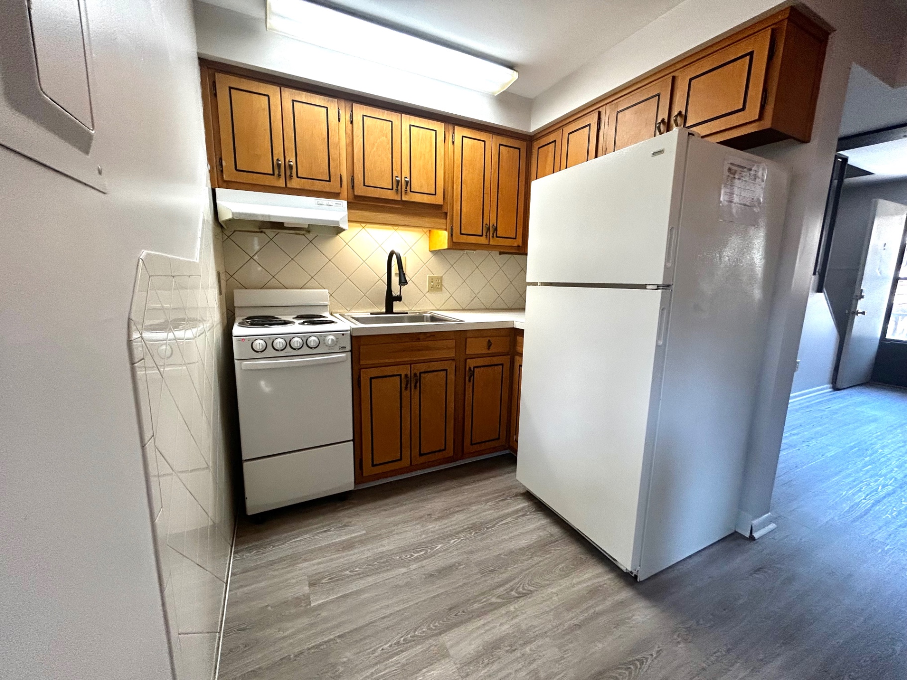 2011 Summit St. Unit E kitchen with wood cabinets, updated faucet, and diamond-set tile backsplash