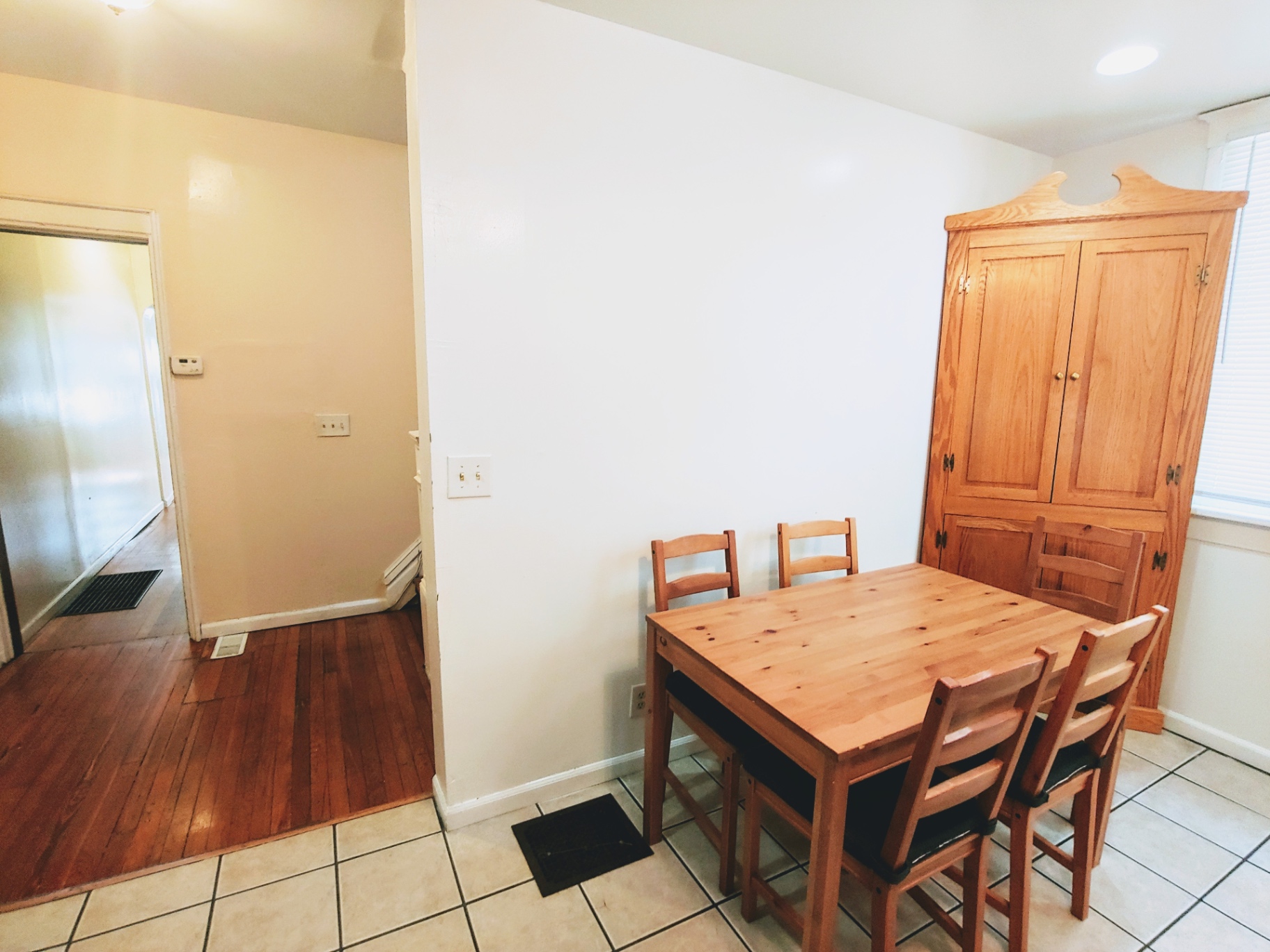 1818 Summit St. dining nook with wood table, storage armoire, and hardwood floors leading to hallway