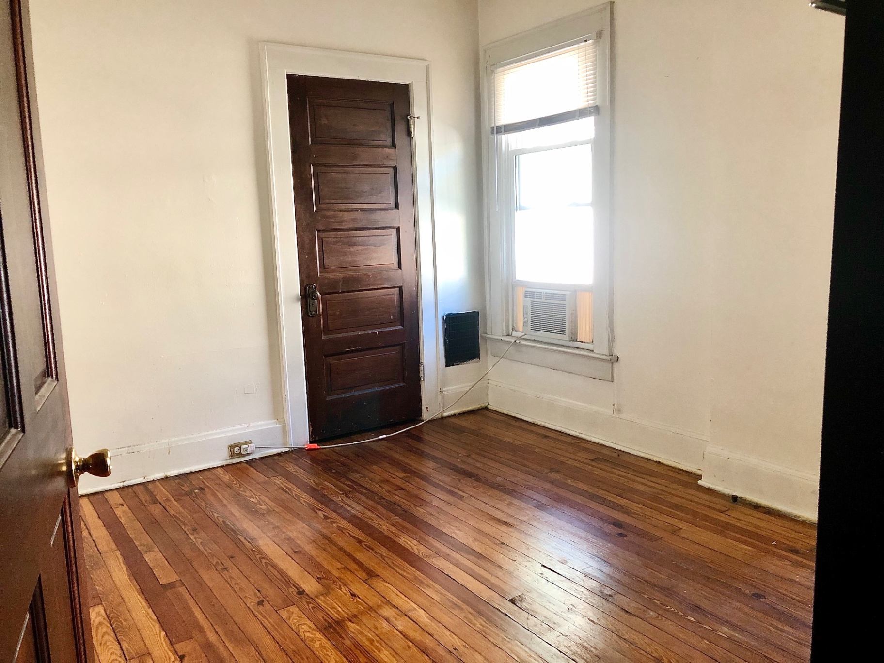 372 B E 14th Ave. bedroom with hardwood floors, window AC, and dark wood door