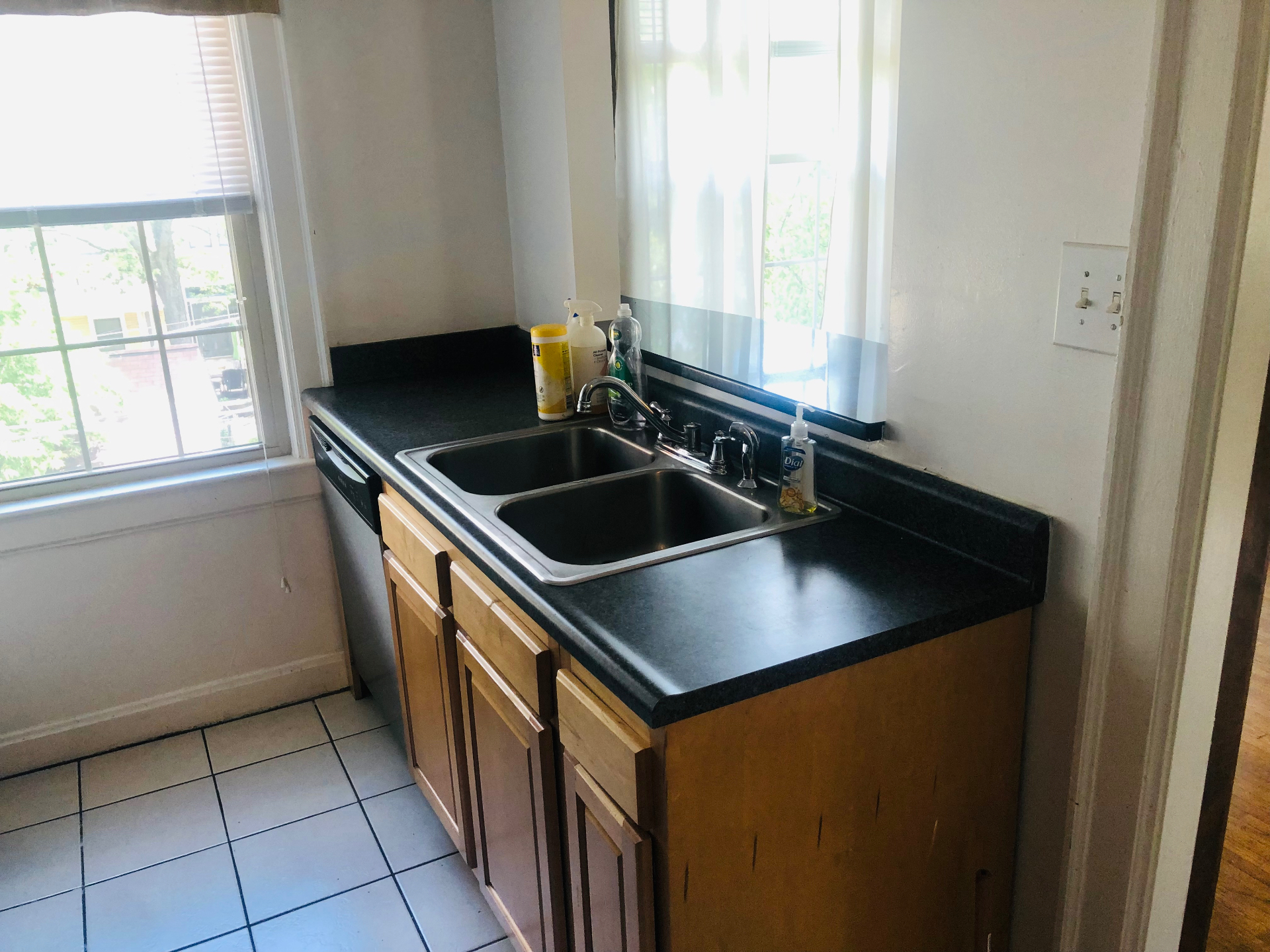 Unit K kitchen with double stainless steel sink, dishwasher, and tile floor