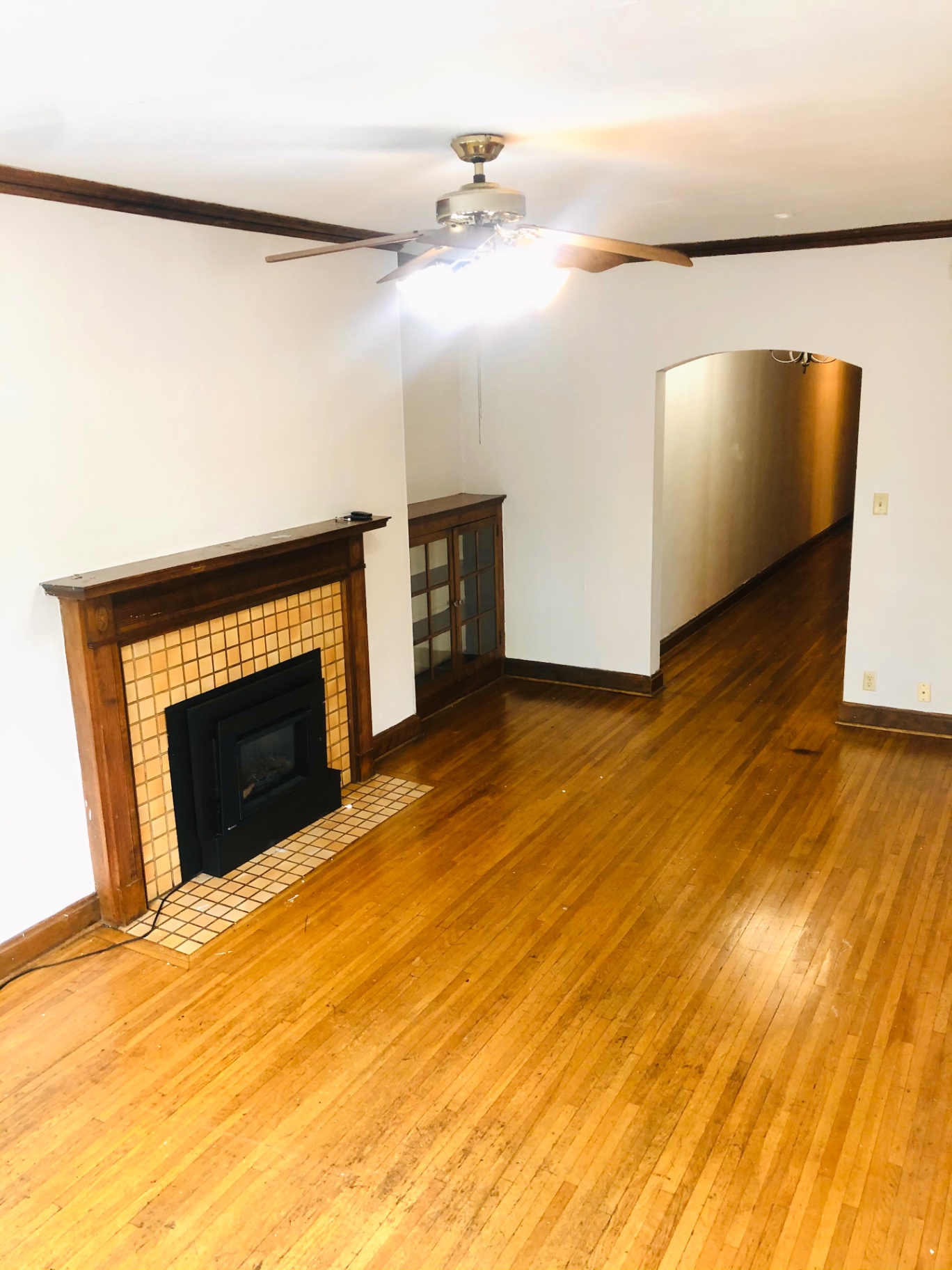 Unit L living room with fireplace, built-in glass cabinet, and archway to dining area