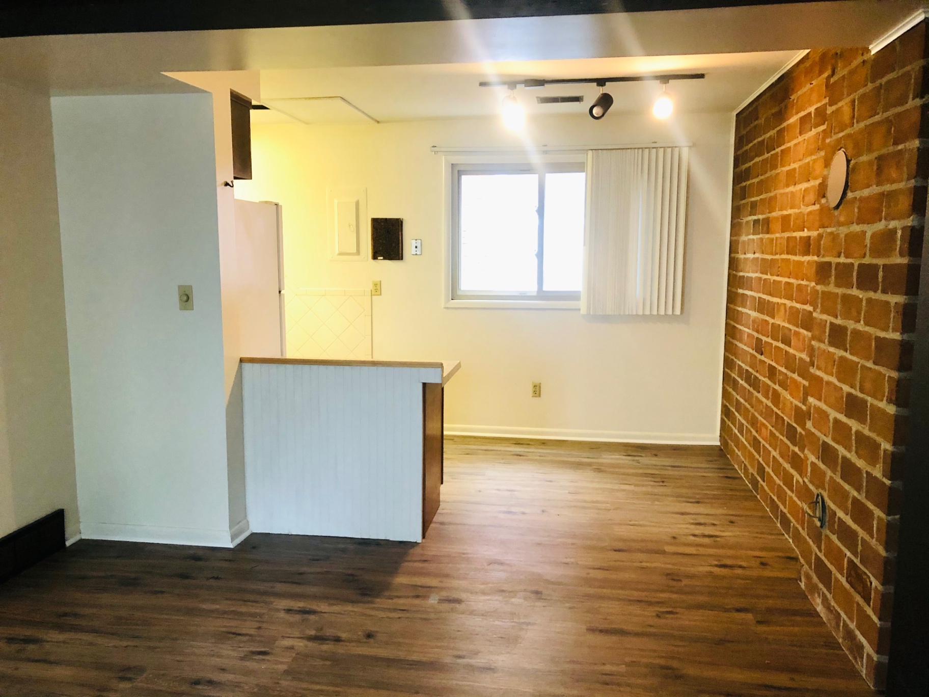 2011 Summit St. Unit B open dining/living area with exposed red brick accent wall, plank floors, and kitchen pass-through