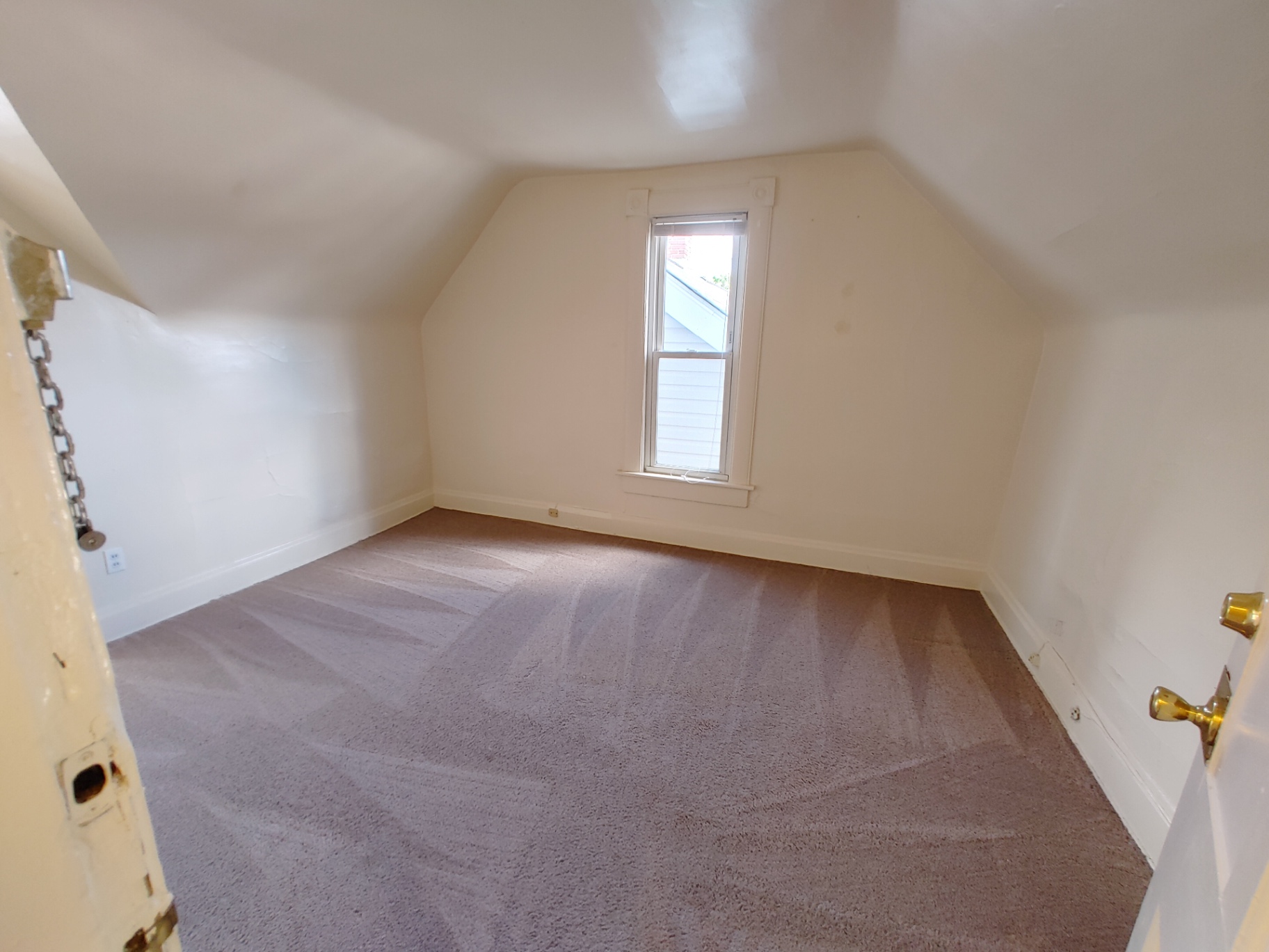 Rear unit upstairs bedroom with vaulted ceiling and tall window