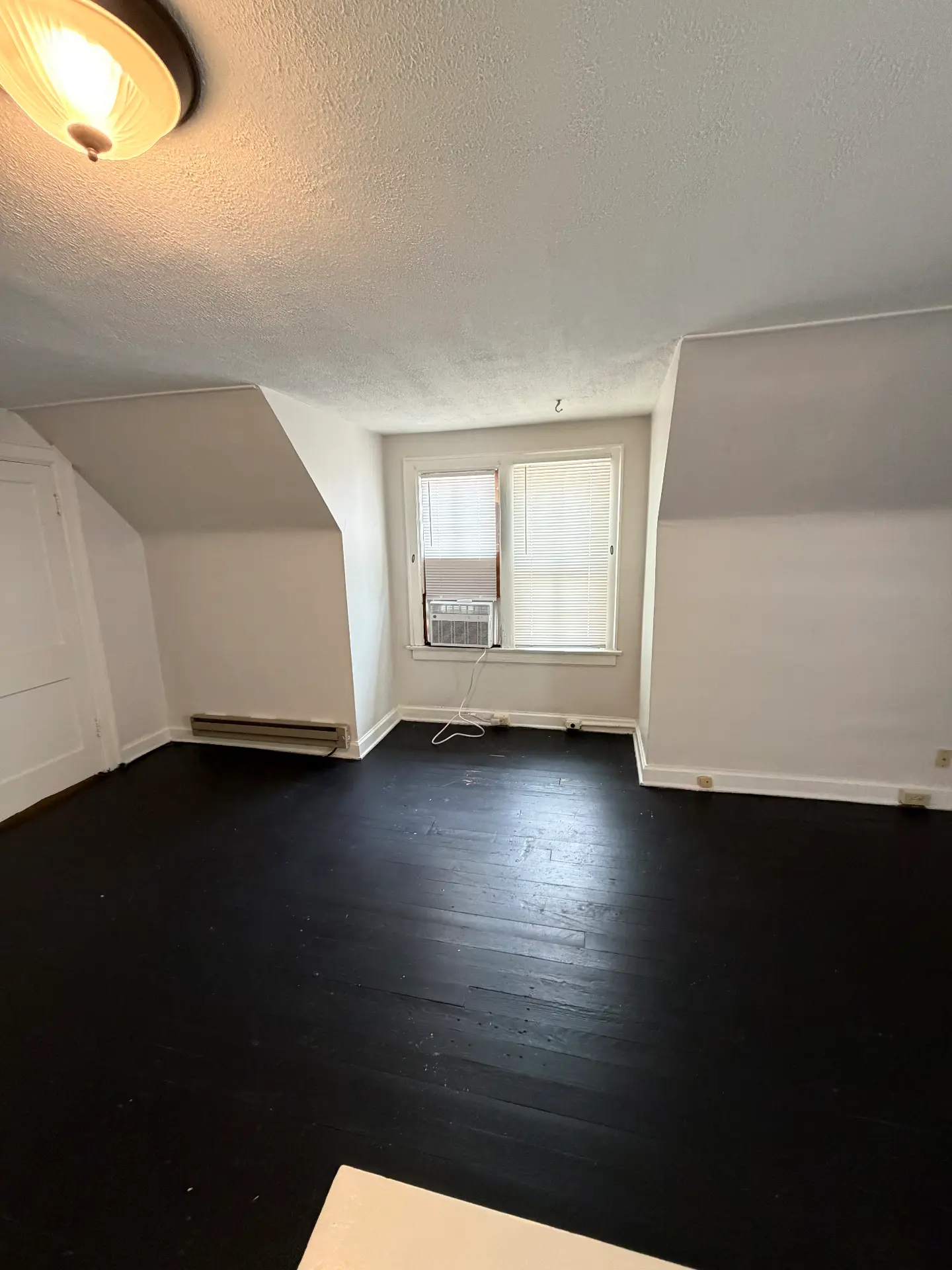 2048 Iuka Ave. D upstairs bedroom with double window, window A/C unit, and painted black hardwood floors