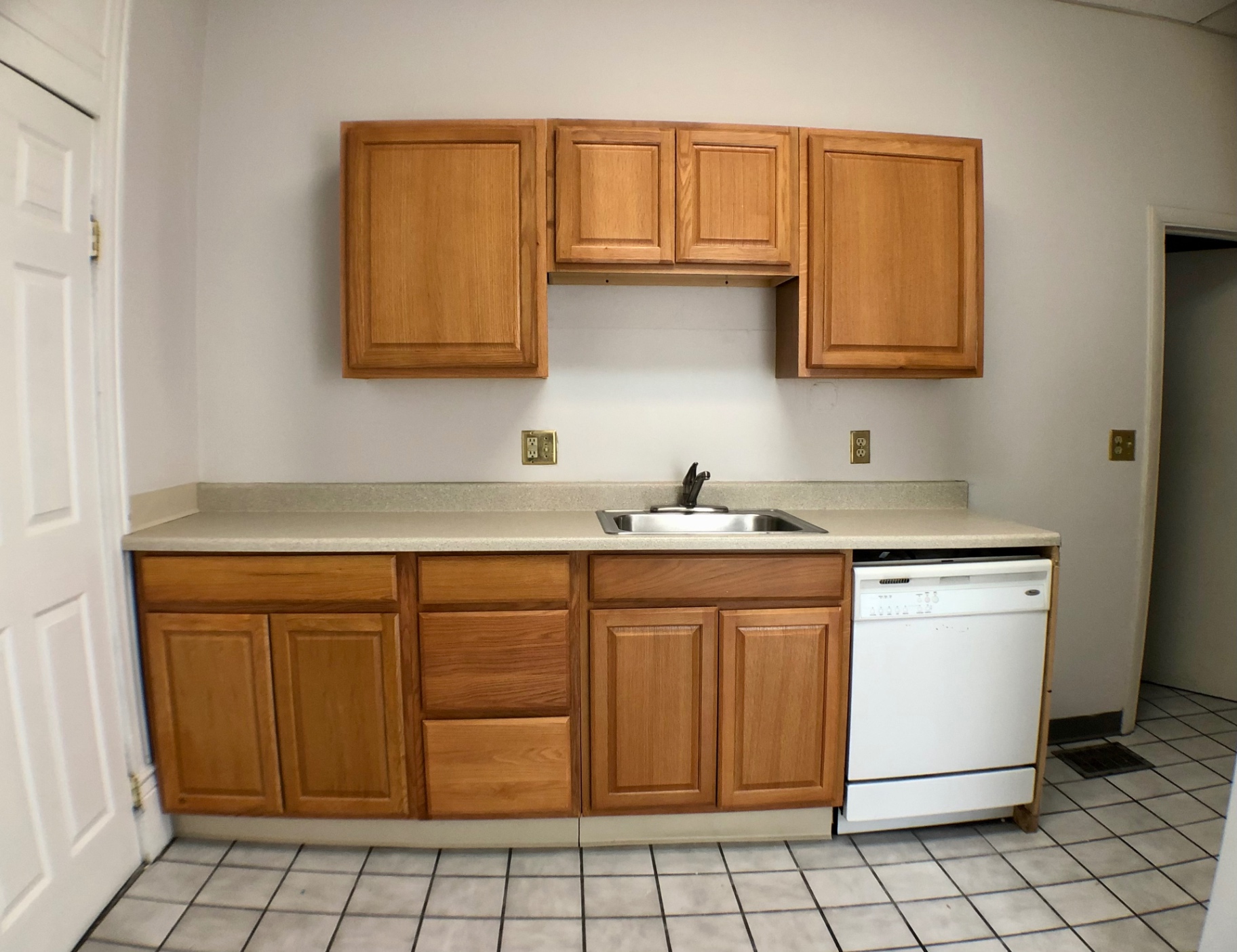 Unit A kitchen with maple cabinets, dishwasher and tiled floor
