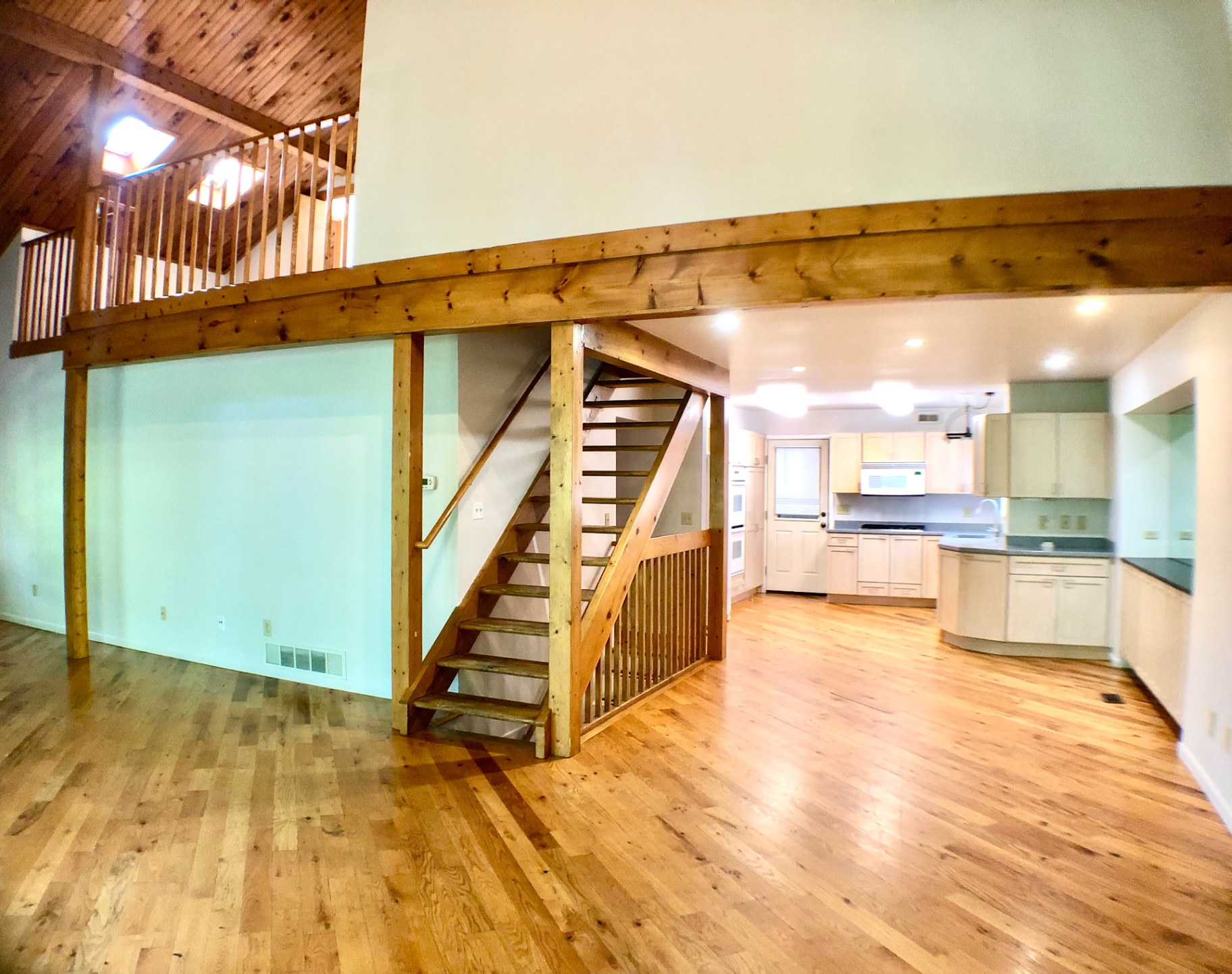 2040 Iuka Ave House open living area with loft above, wood staircase, and kitchen beyond