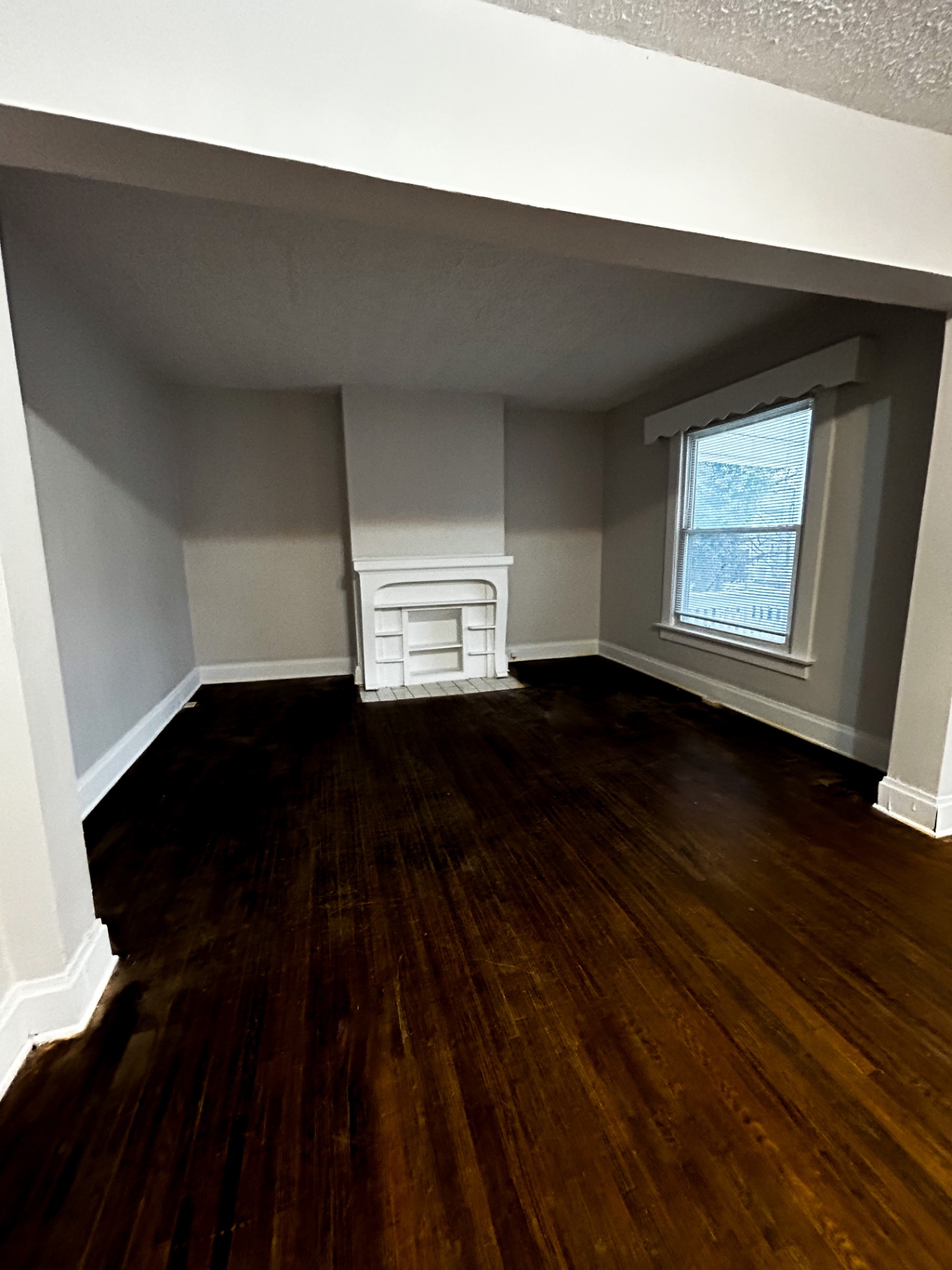 68 E Patterson Ave. living room with original white mantel fireplace, dark hardwood floors, and large window