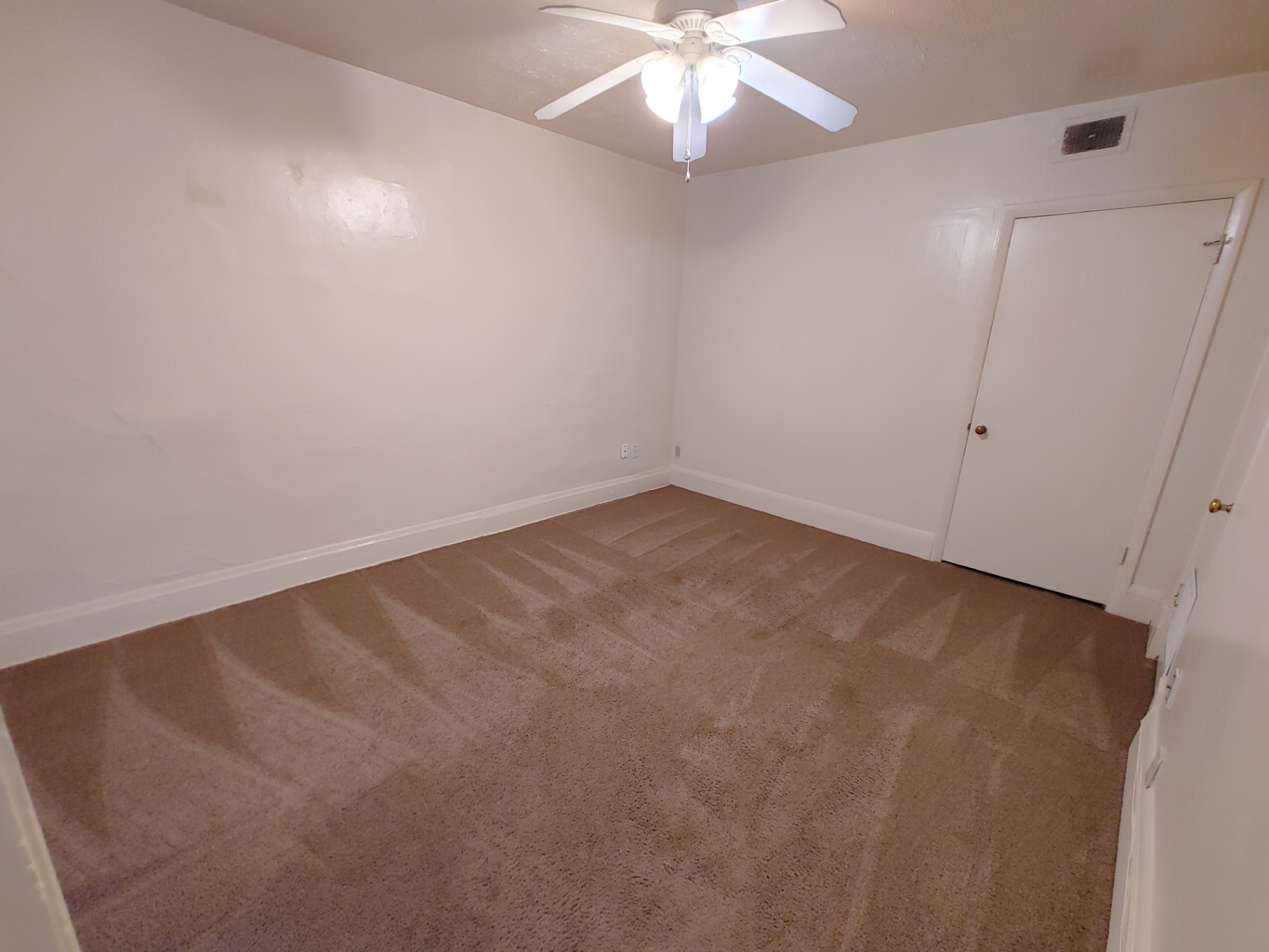 Rear unit main-floor bedroom with ceiling fan and fresh carpet