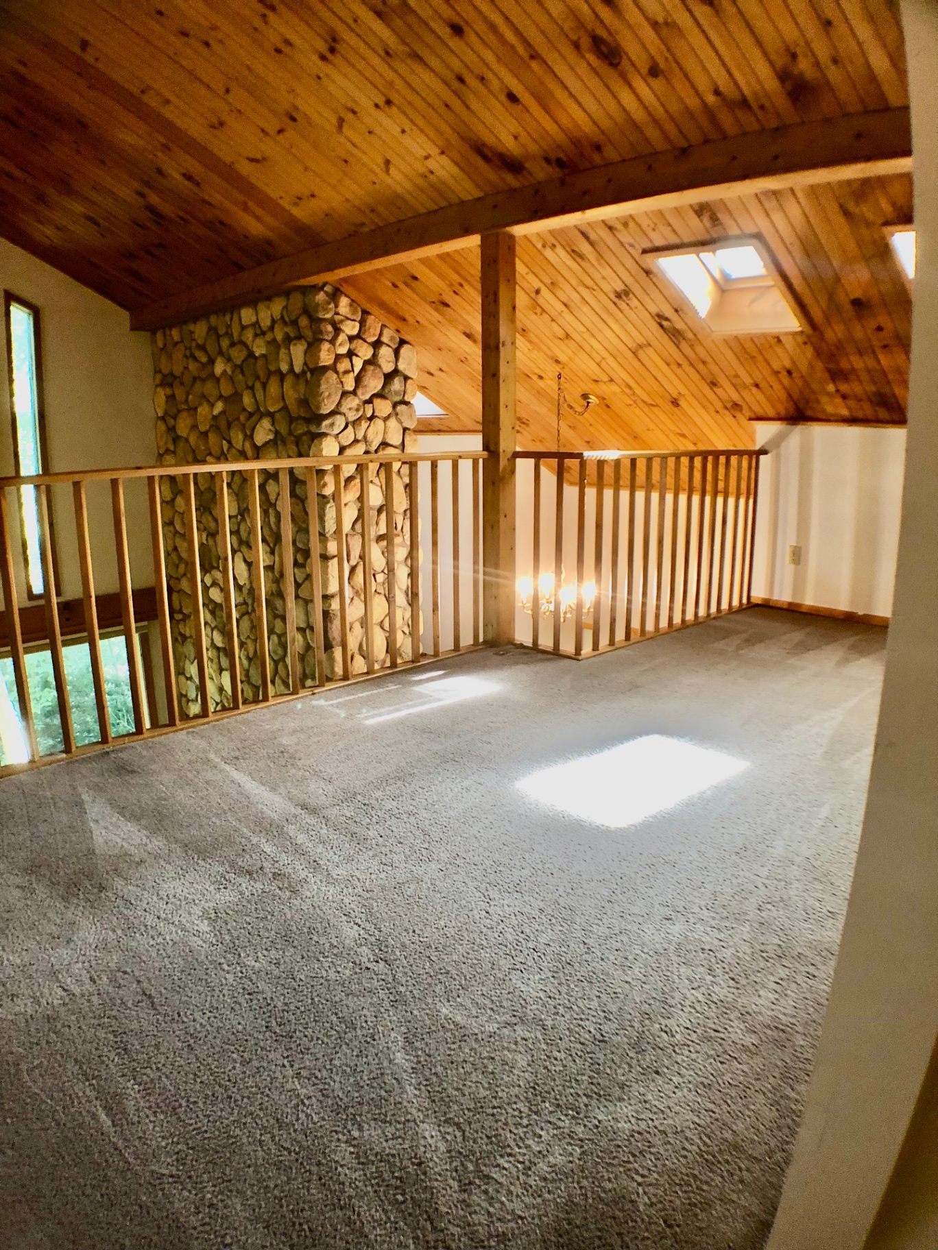 2040 Iuka Ave House upstairs loft with skylights, tongue-and-groove wood ceiling, and stone chimney wall