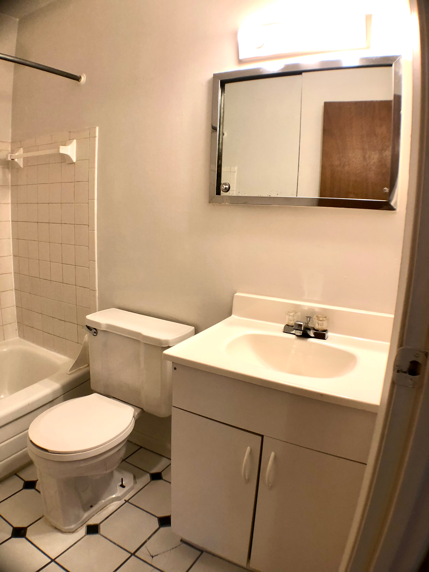 1827 N 4th St. Unit 4 bathroom with white vanity, tiled tub surround, and checkered tile floor