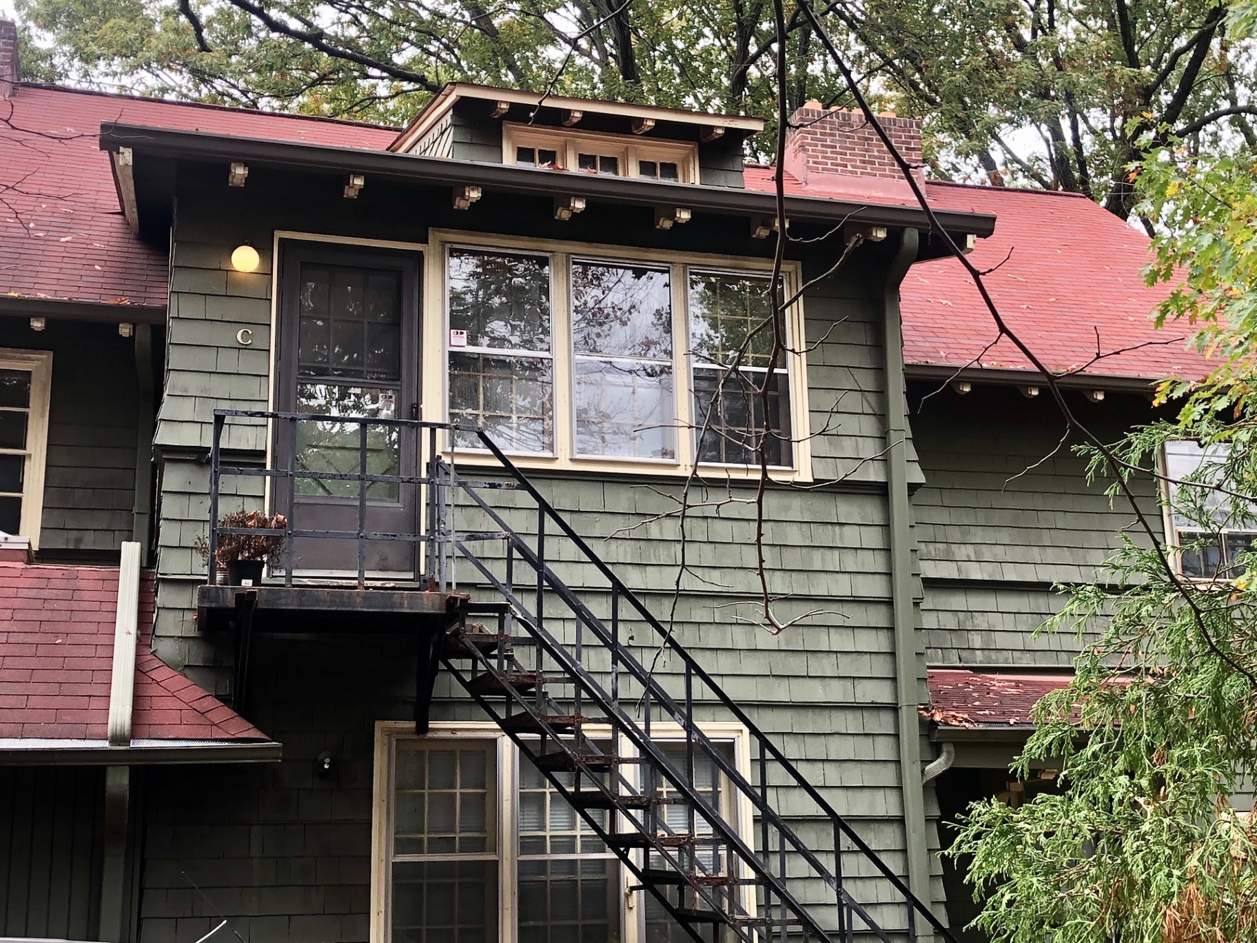 2026 Iuka Ave C exterior with green shake siding, red roof, and private balcony entry