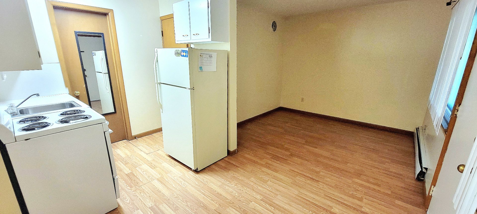 2040 Iuka Ave. 3A open kitchen and living area with wood laminate floors and full-size refrigerator