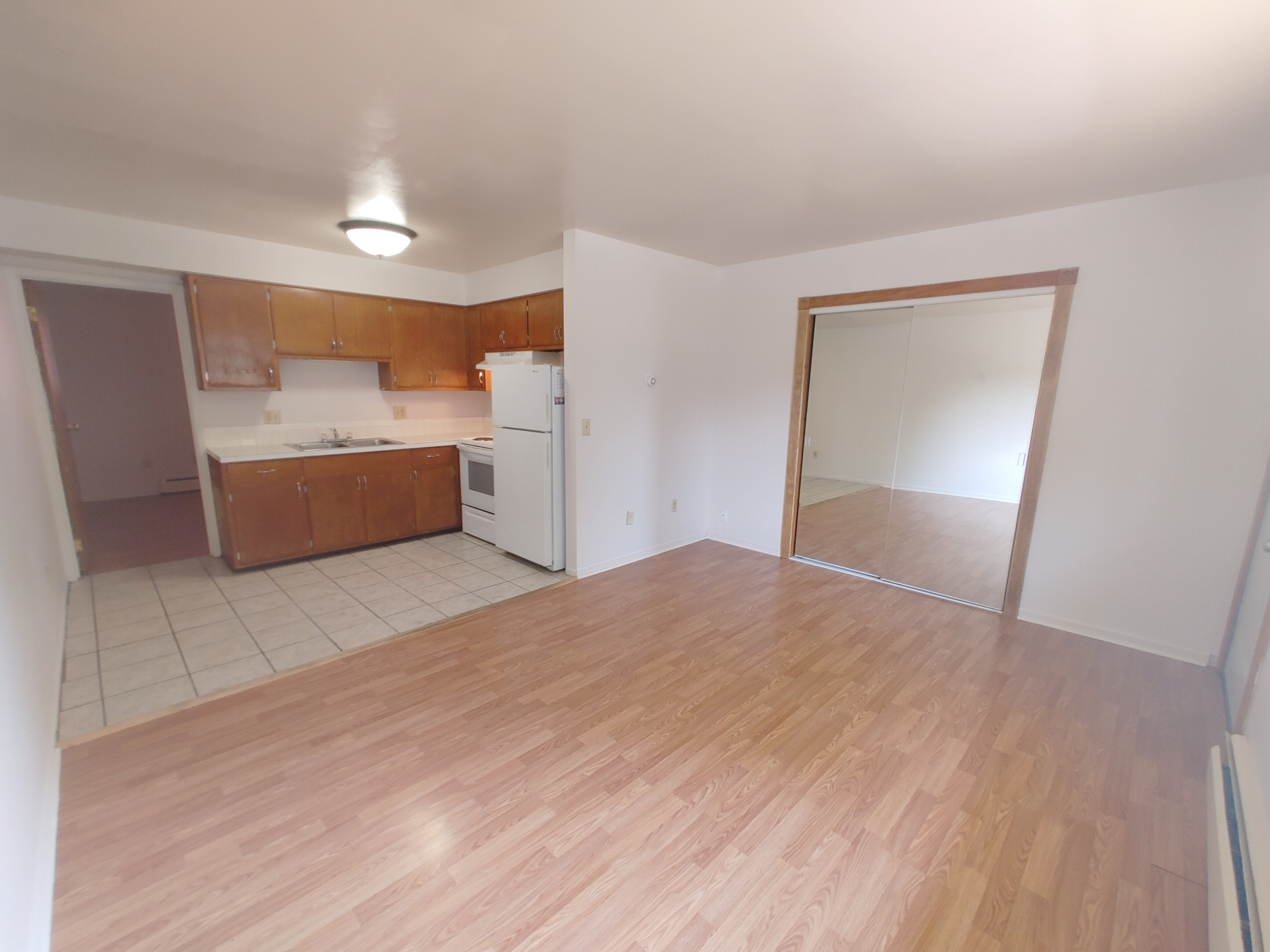 1827 N 4th St. Unit 5 open living area with wood-look flooring, mirrored closet doors, and adjacent tile kitchen